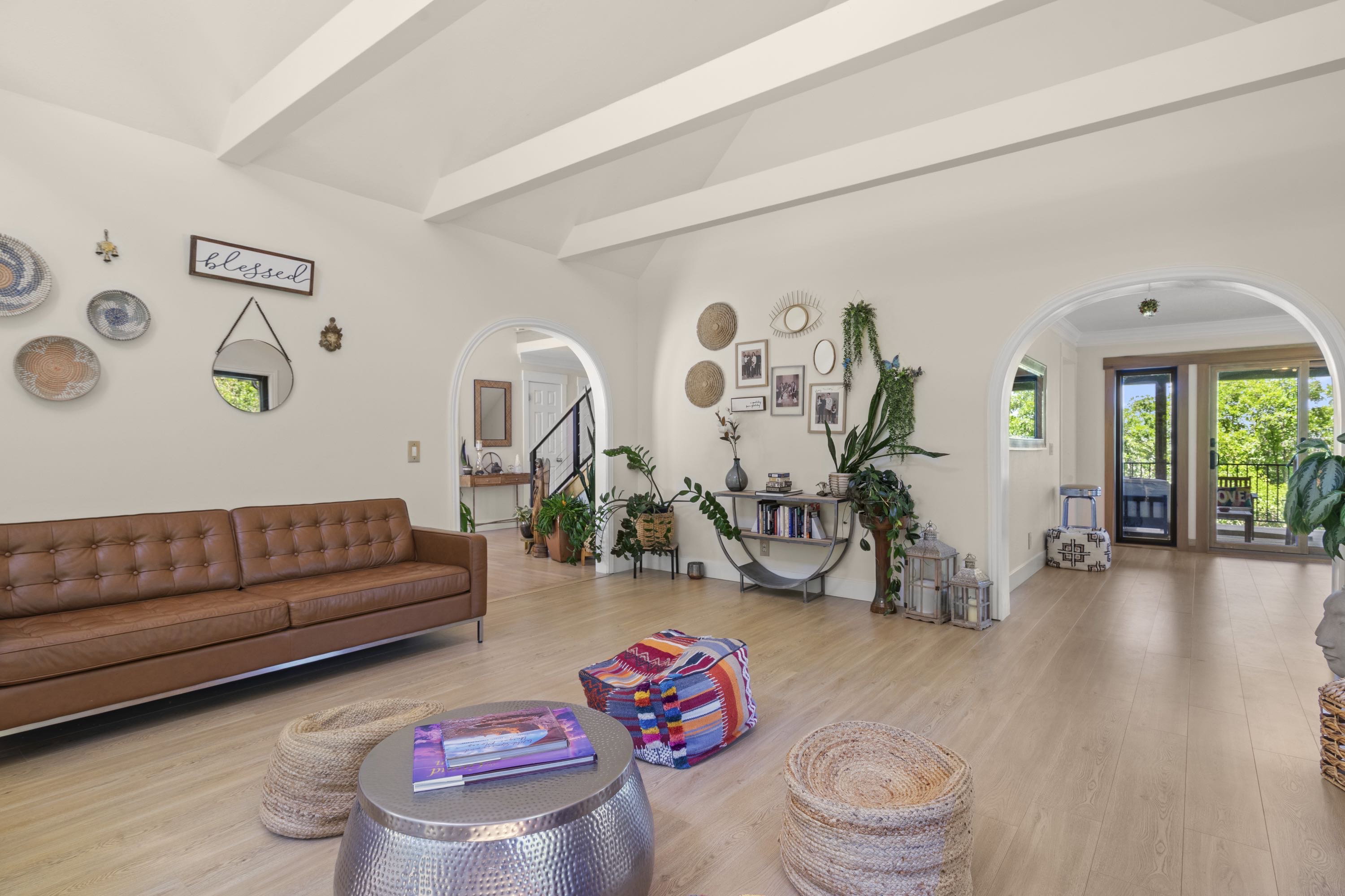 Spacious living area featuring light wood-finish flooring and exposed ceiling beams