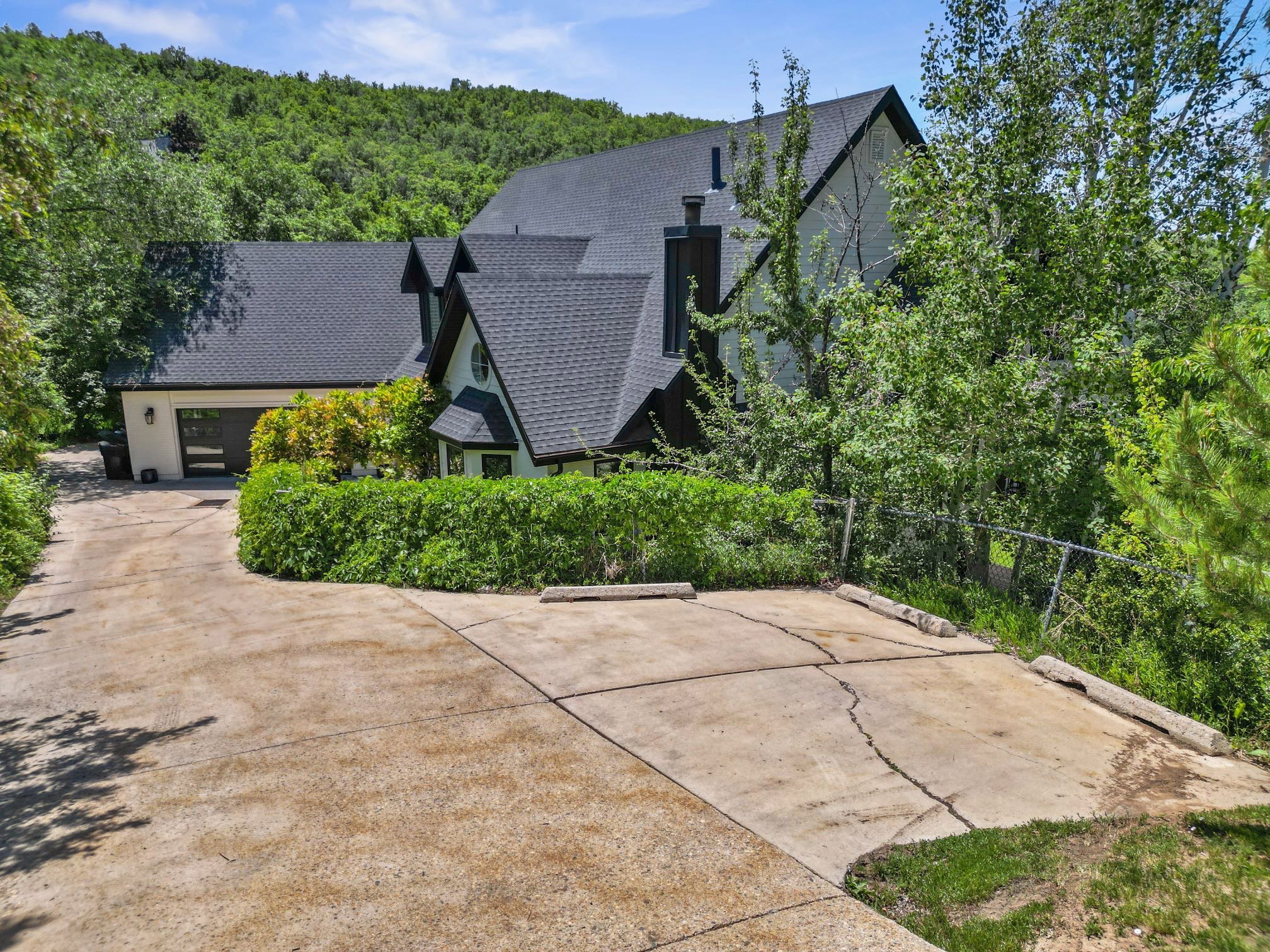 Multi-gabled residence featuring dark roofing and light-toned siding