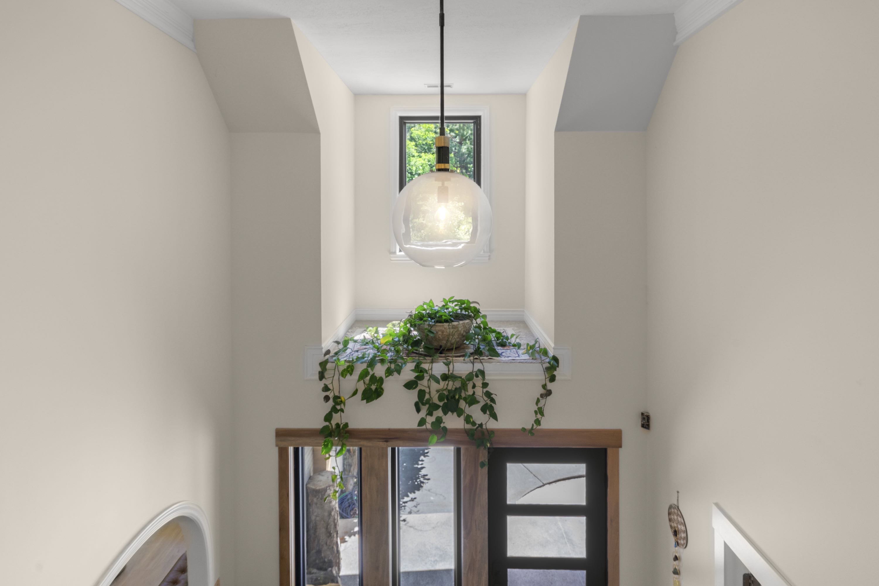 Two-story entryway featuring a black-framed window and a modern glass pendant light