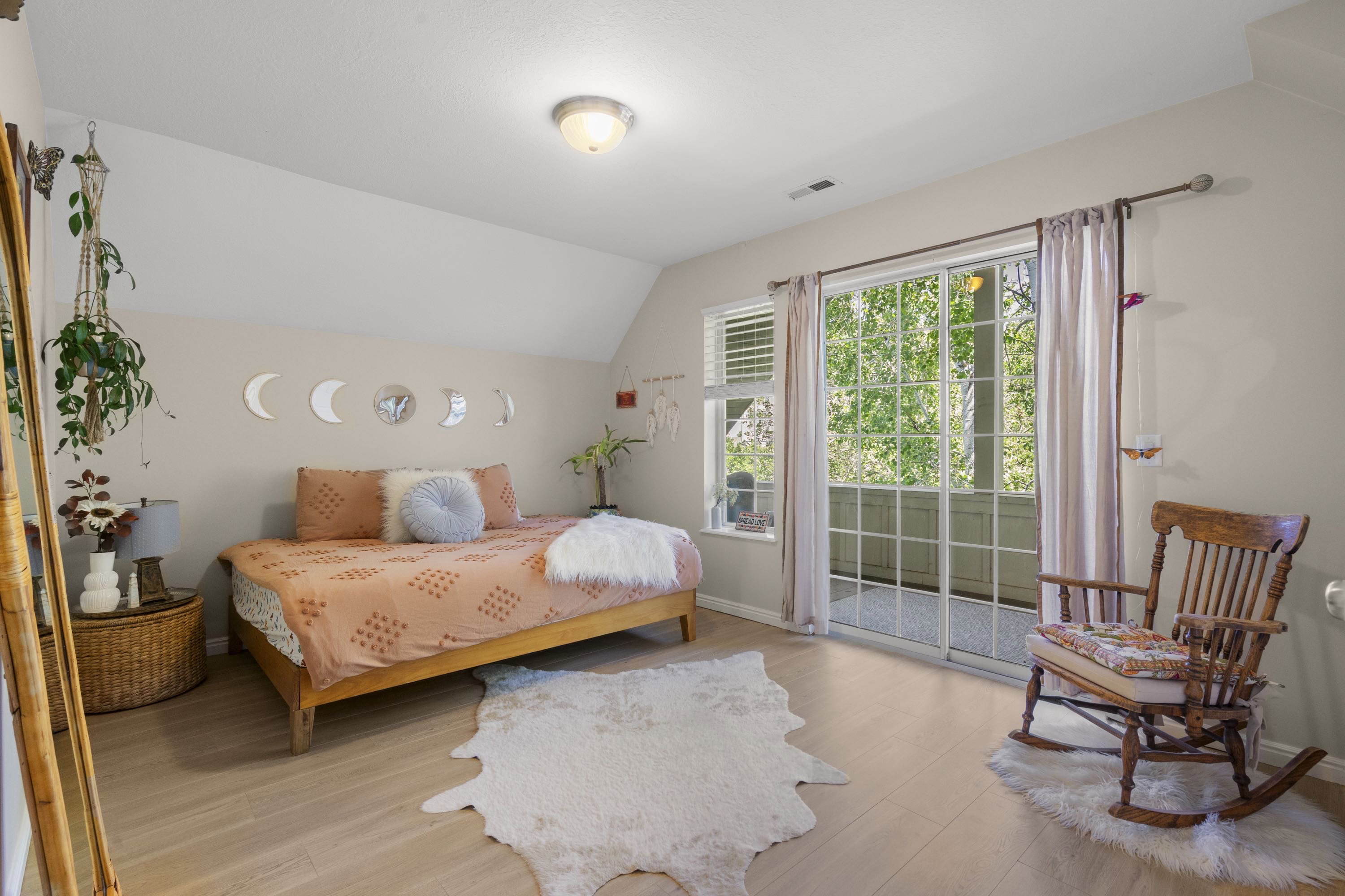 Living area featuring light wood-finish flooring, a vaulted ceiling, and a glass sliding door leading to an outdoor space