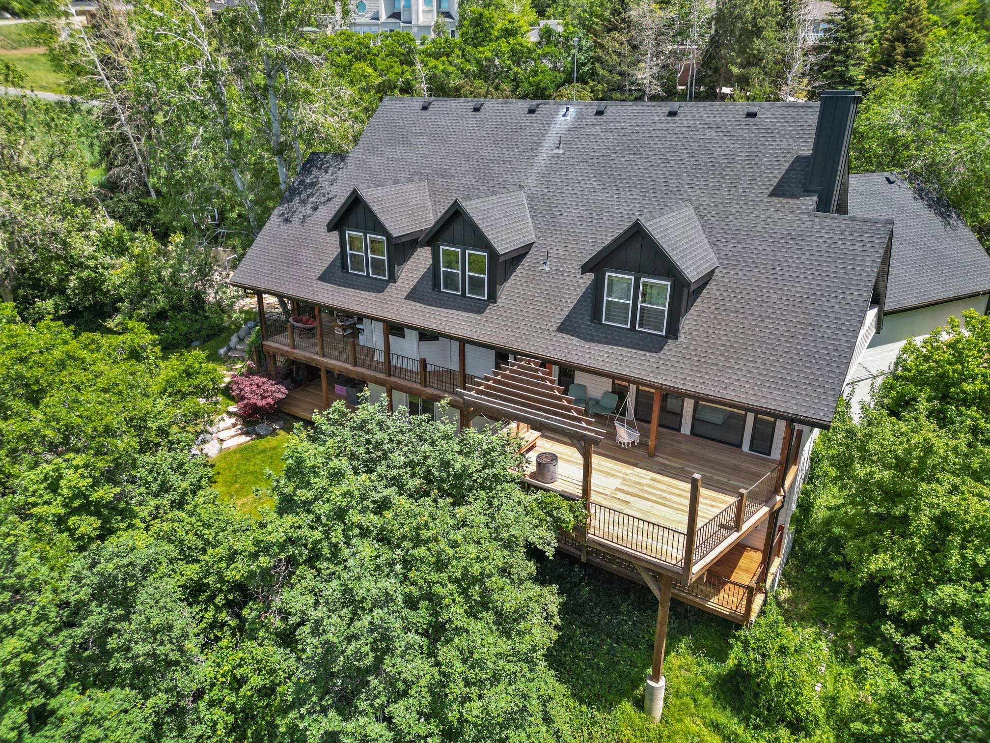 Multi-level residence featuring a dark shingle roof, multiple dormer windows, and a prominent black chimney