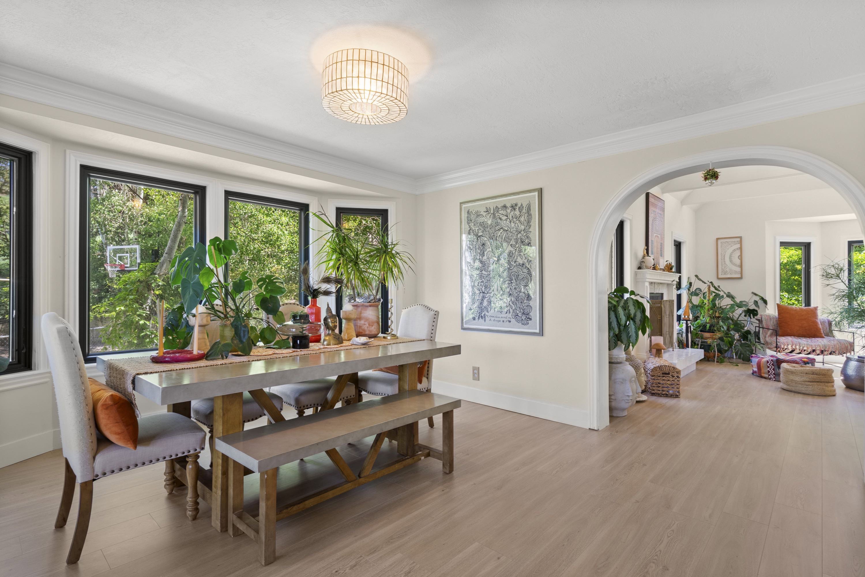 Bright dining area featuring a bay window with black trim, crown molding, and wood-finish flooring