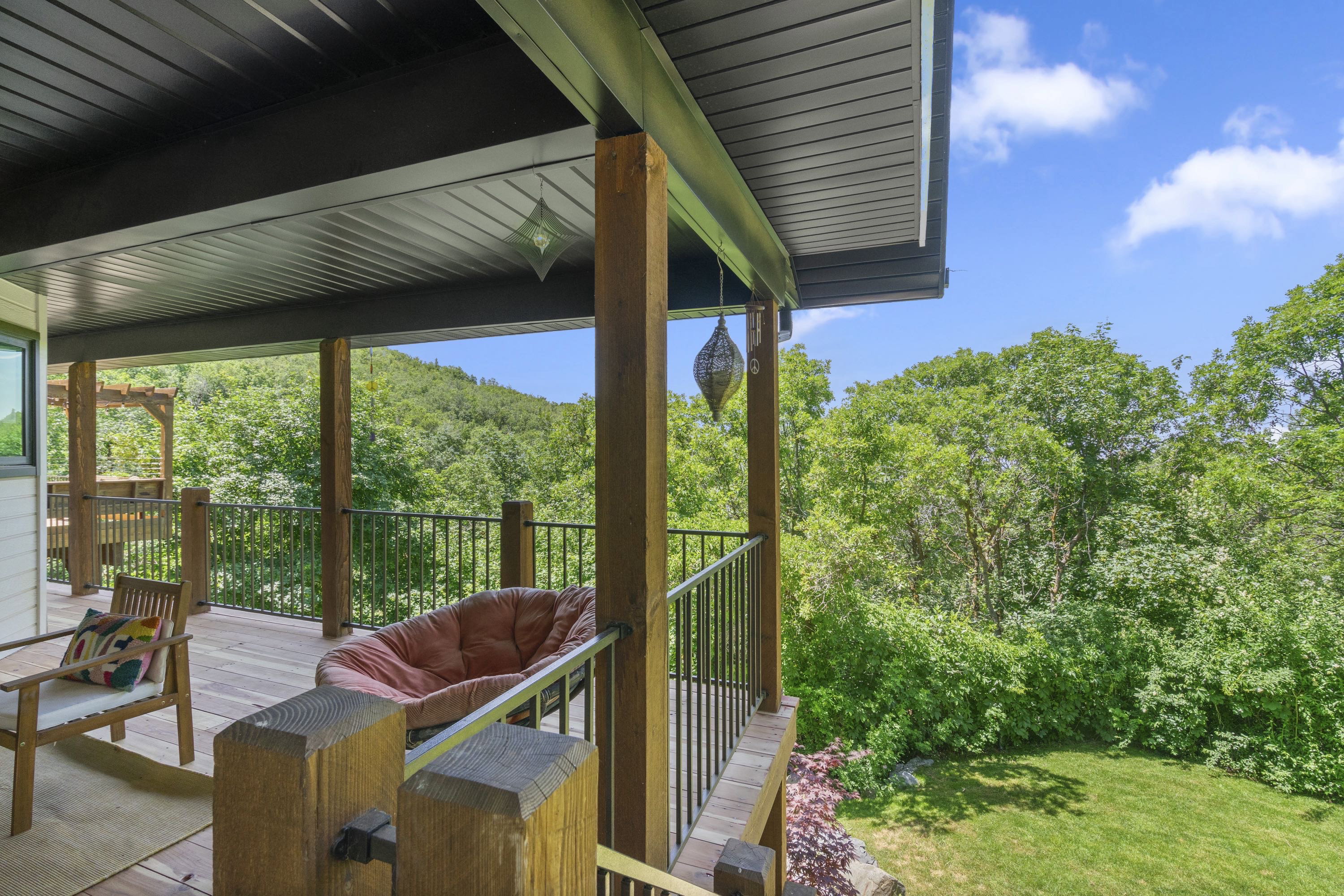 Covered outdoor deck with wood flooring and dark metal railings