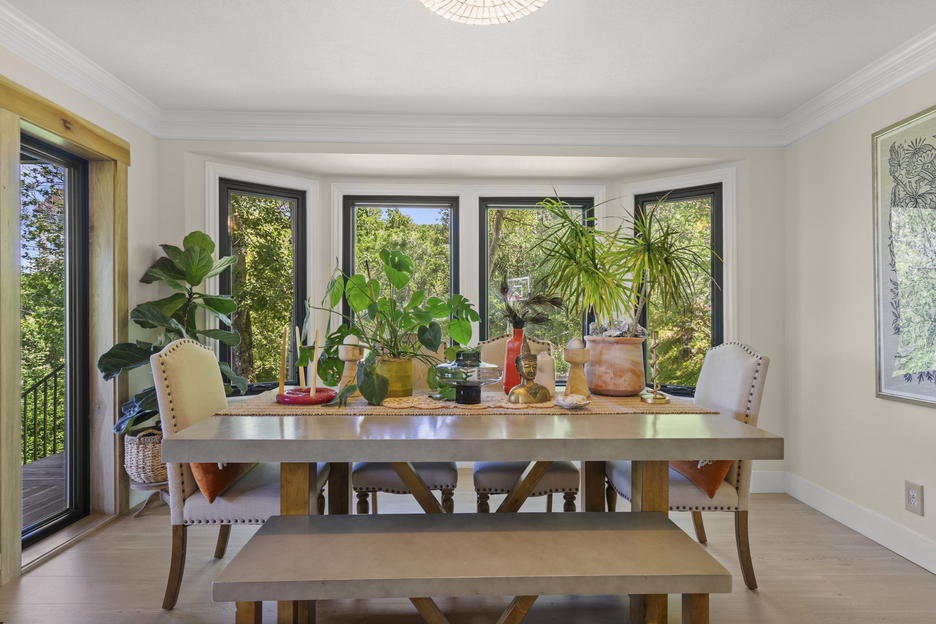 Bay window with black trim, crown molding, light wood-finish flooring, and a sliding glass door