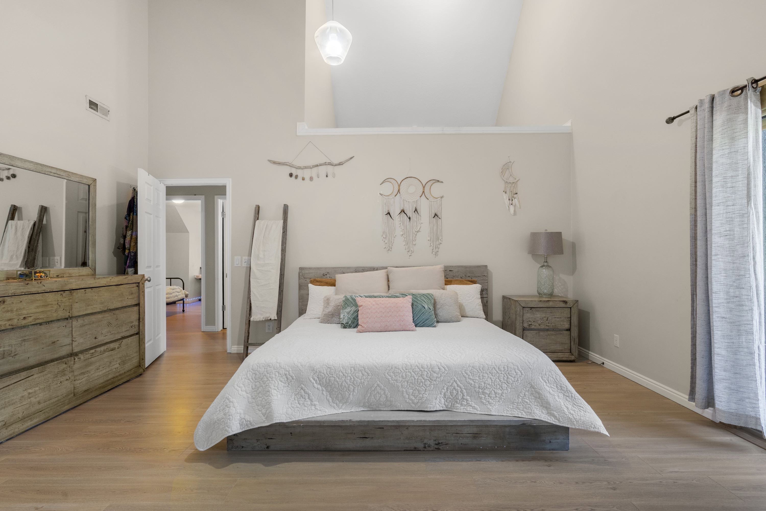 Bedroom featuring vaulted ceiling, light wood-finish flooring, and a glass pendant light fixture