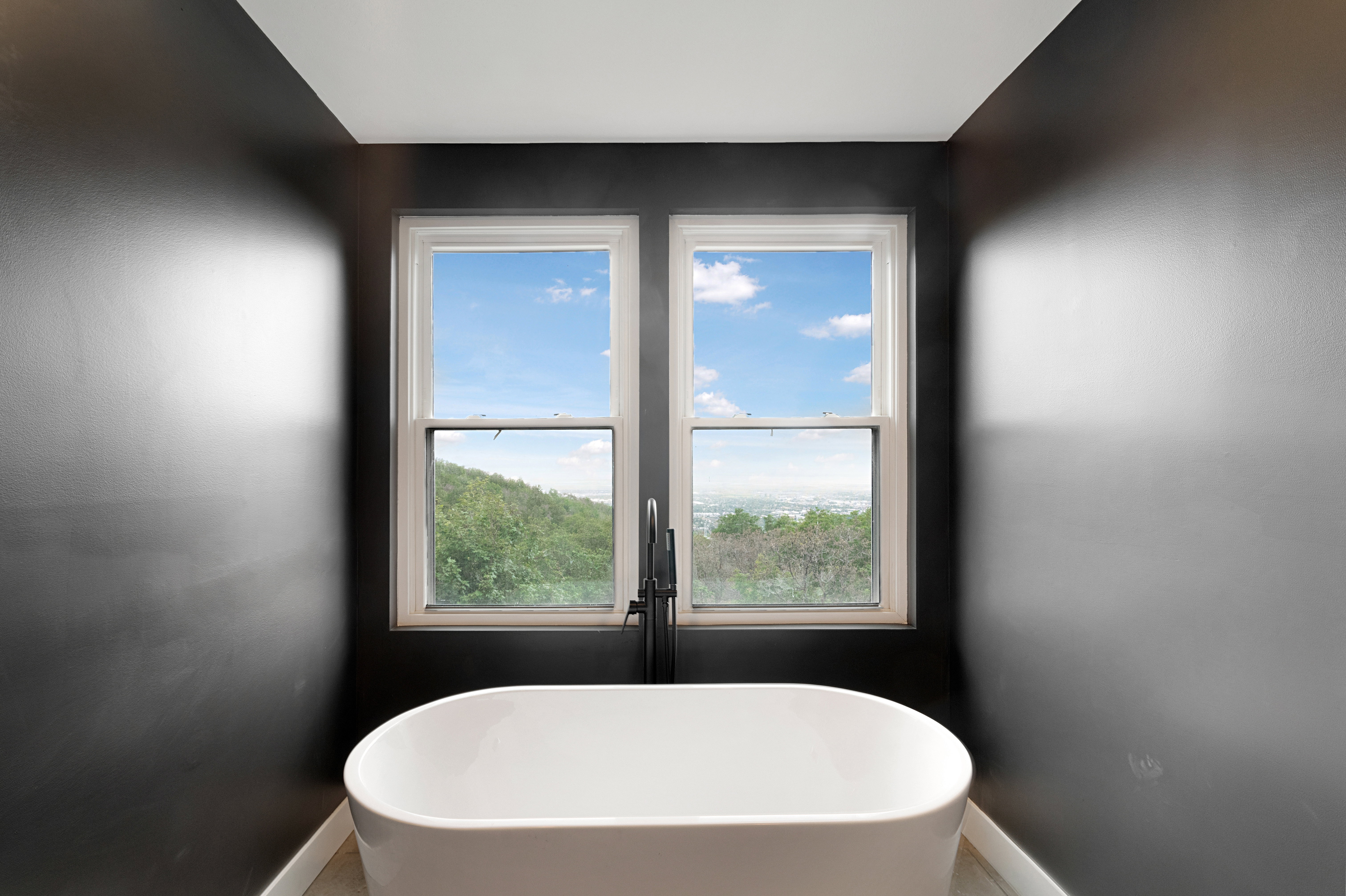 Freestanding soaking tub centered beneath two double-hung windows