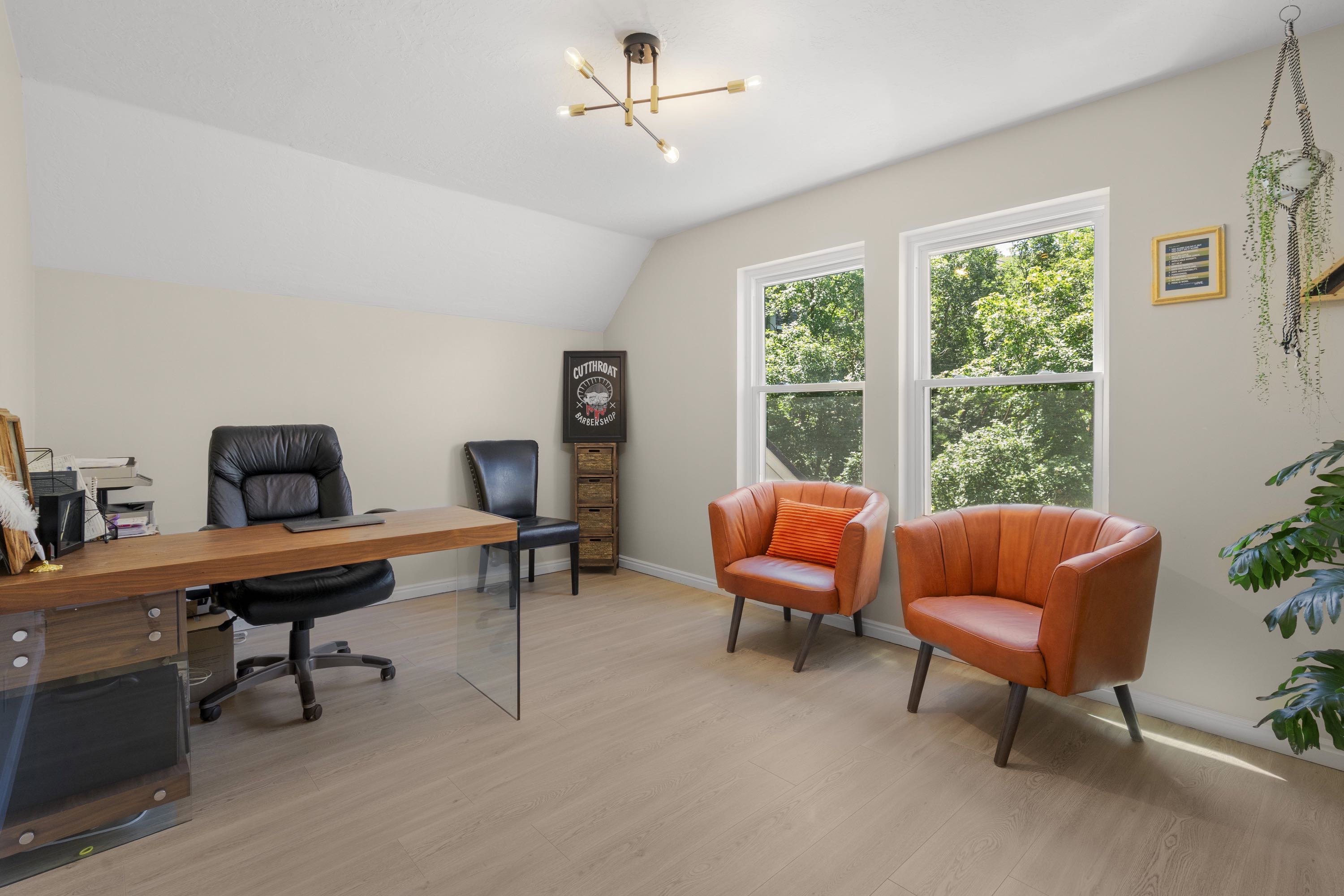 Spacious room featuring light-toned walls, wood-finish flooring, and a contemporary ceiling light fixture