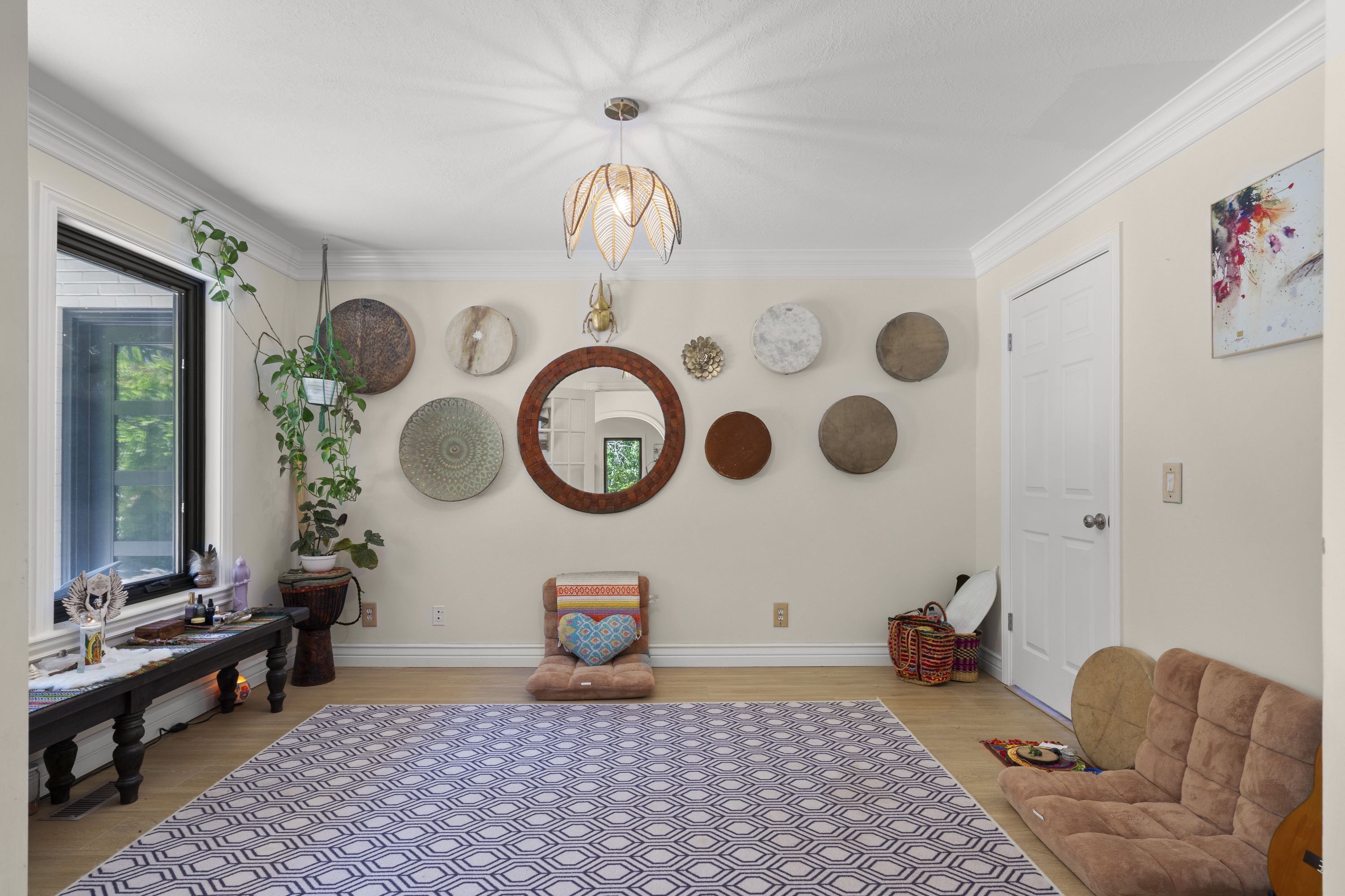 Spacious room featuring wood-finish flooring, crown molding, a large window, a ceiling-mounted light fixture, and a solid white door