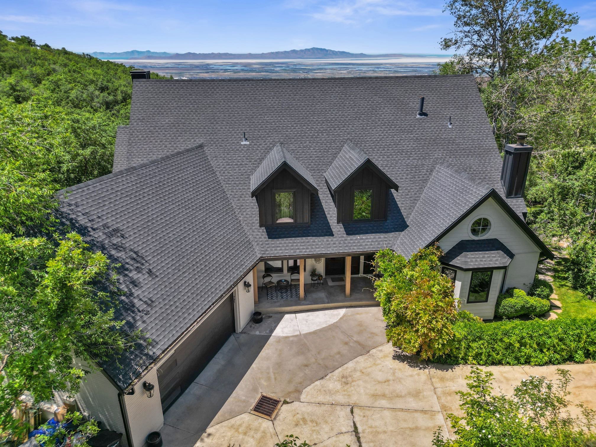 Expansive residence featuring a dark asphalt shingle roof, multiple dormers, and a prominent chimney