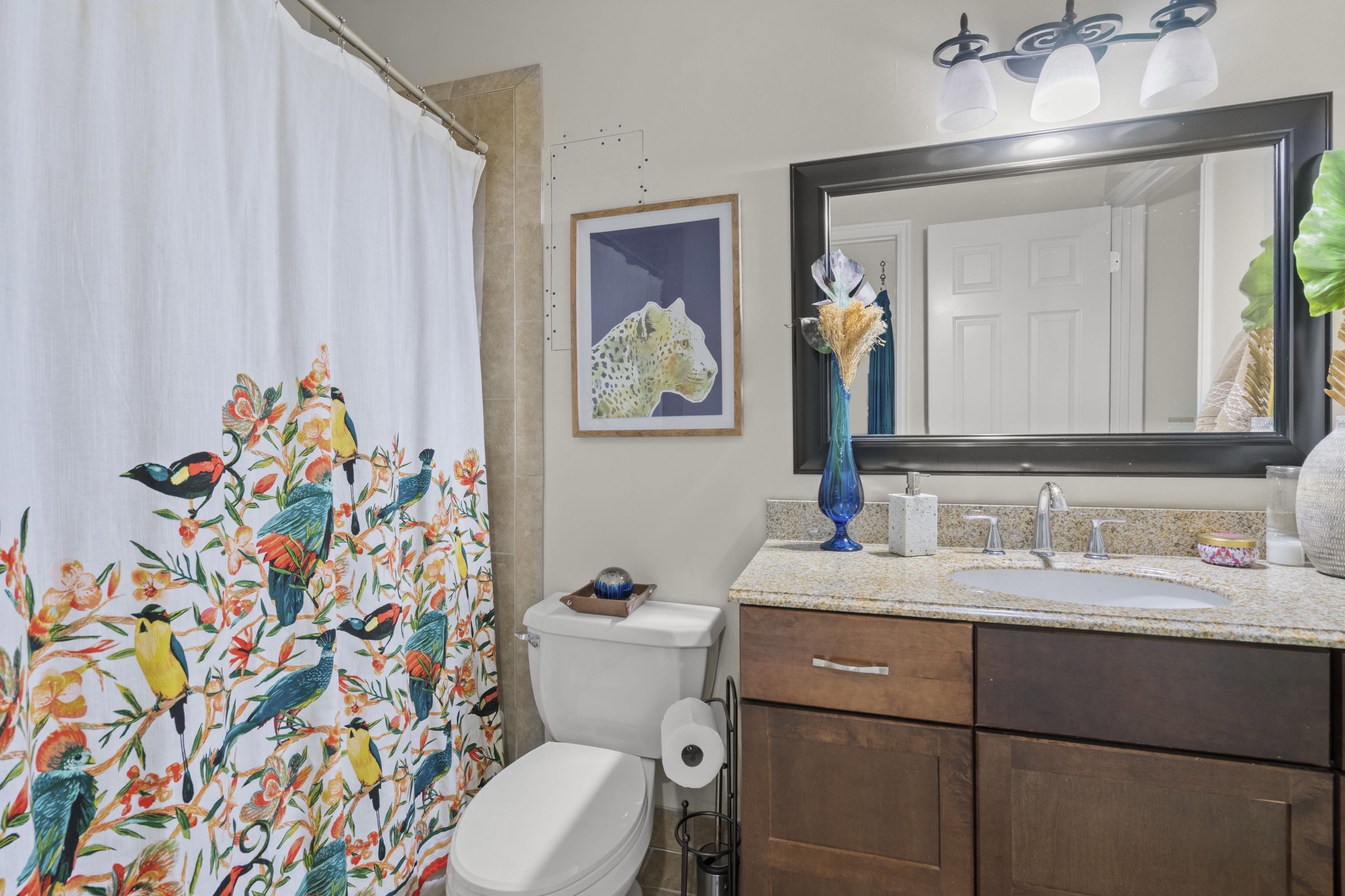 Bathroom featuring a granite countertop, undermount sink, dark wood vanity, and a framed mirror