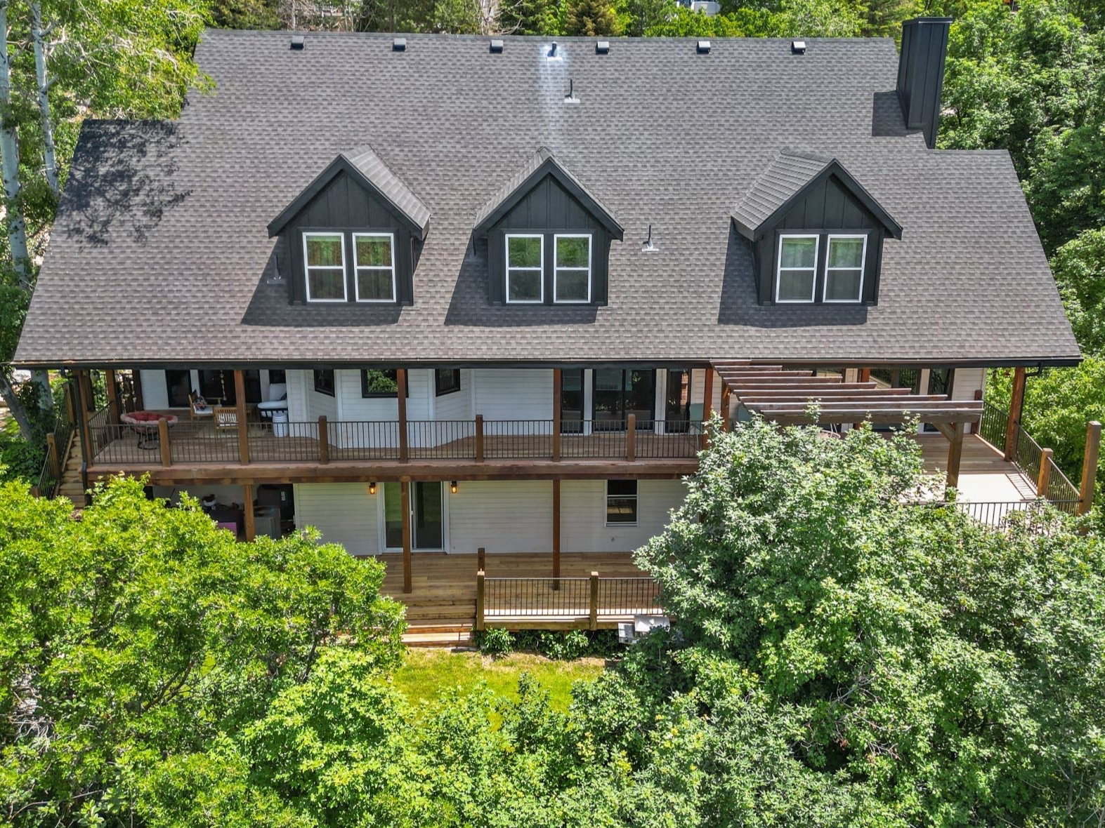 Multi-level residence featuring a dark shingle roof, dark siding accents, and white siding