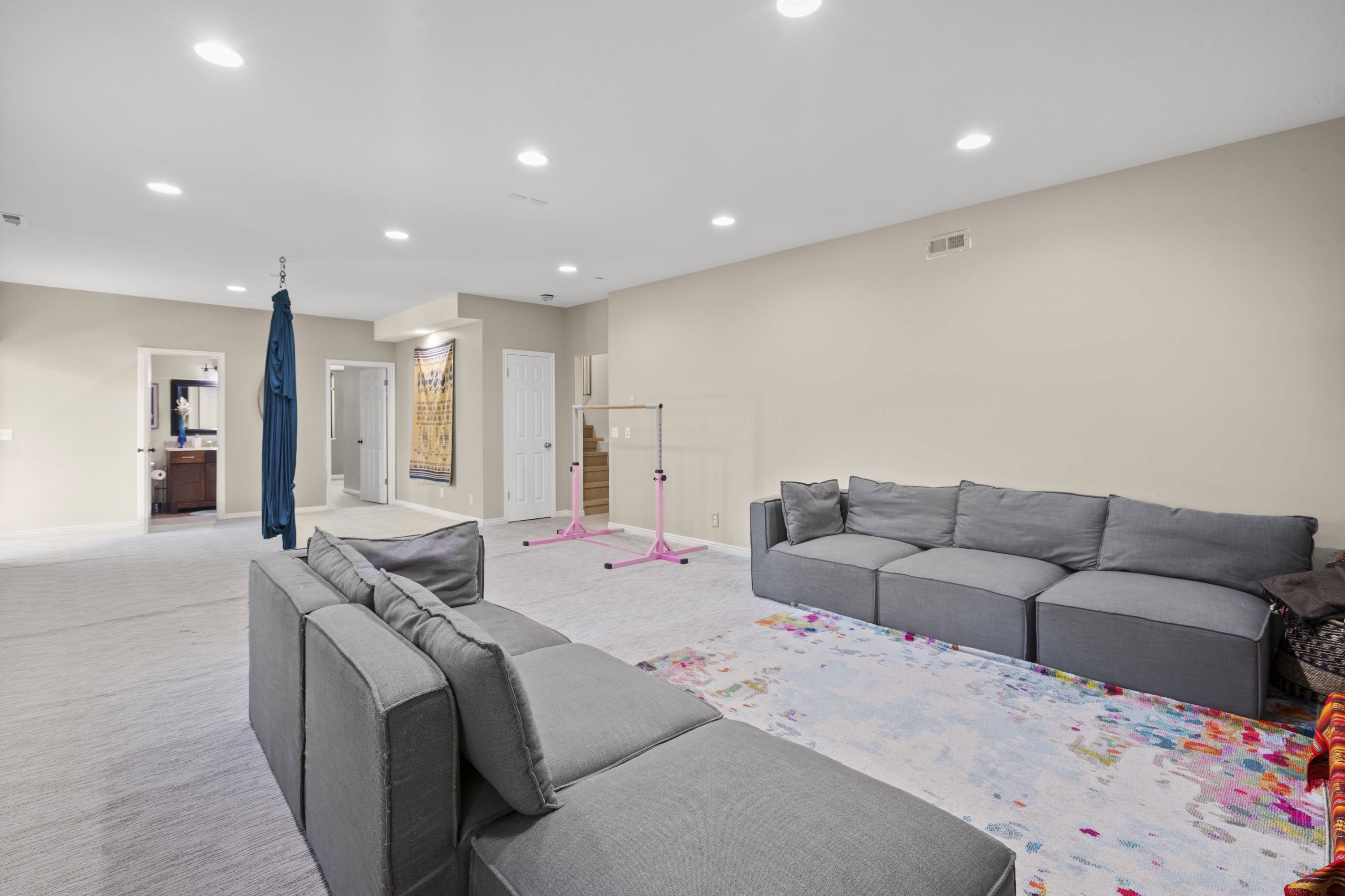 Spacious carpeted room with neutral wall tones, recessed lighting, and multiple doorways