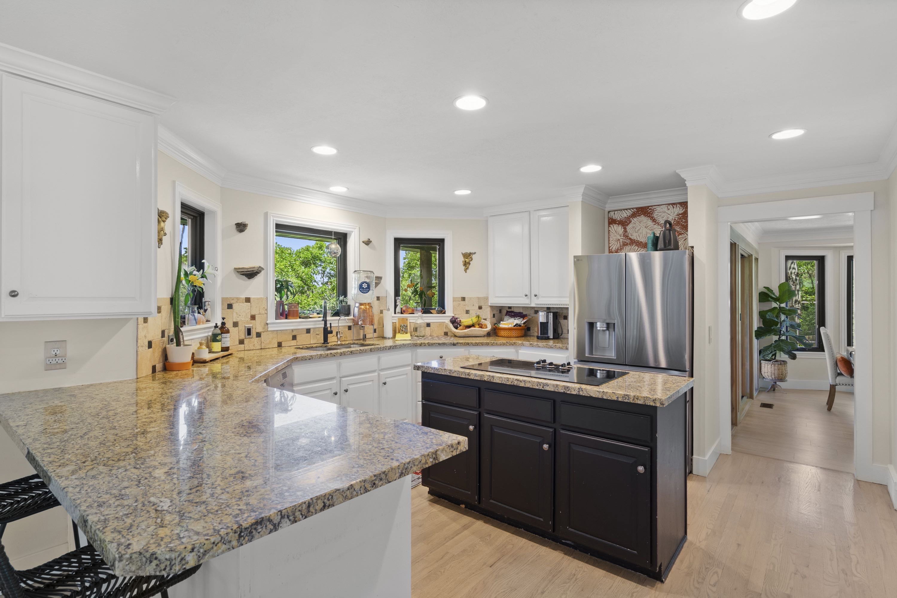 Kitchen featuring light-toned countertops, white upper cabinetry, and a dark-toned island with a built-in cooktop