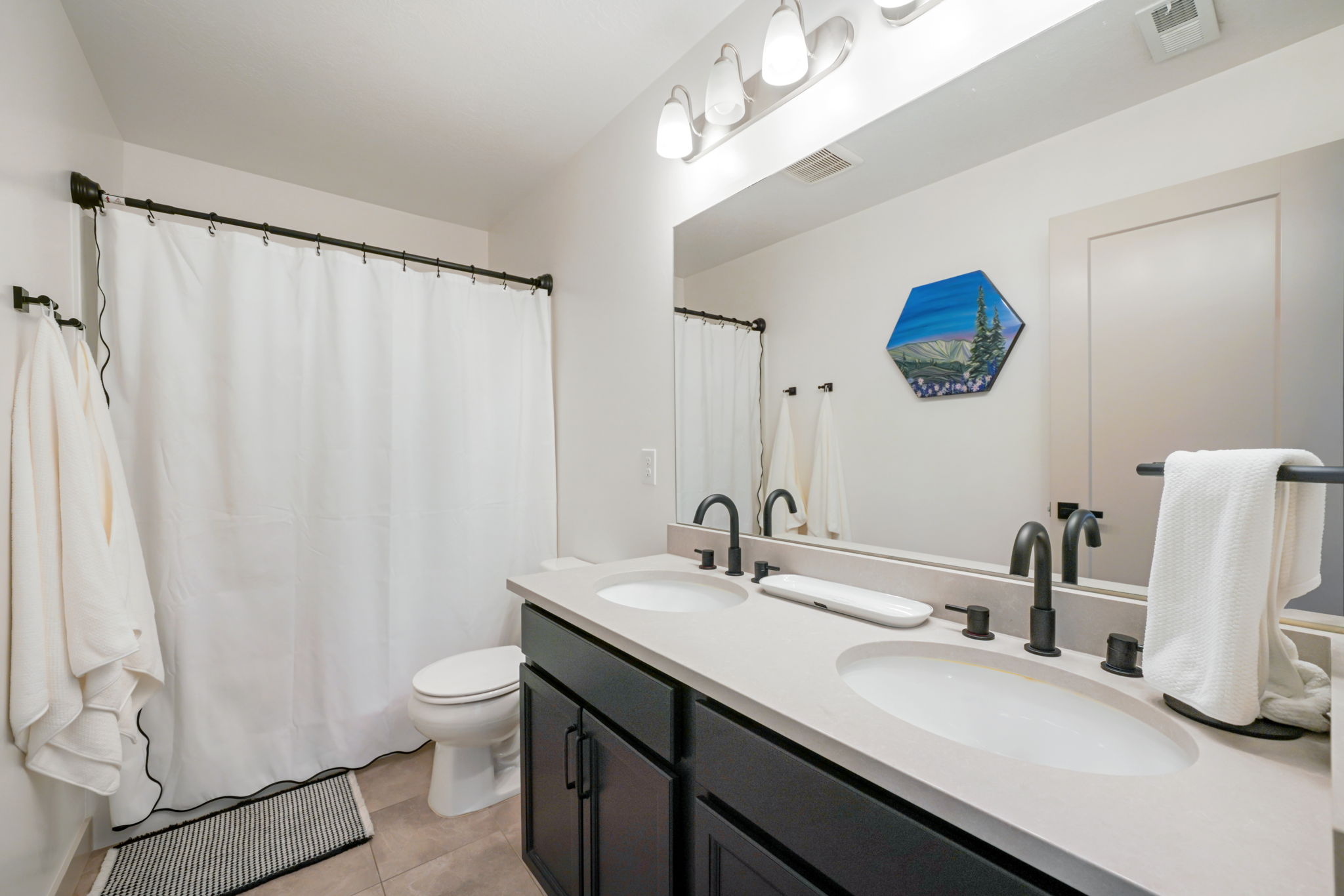 Double vanity with dark cabinetry, light countertop, and matte black fixtures