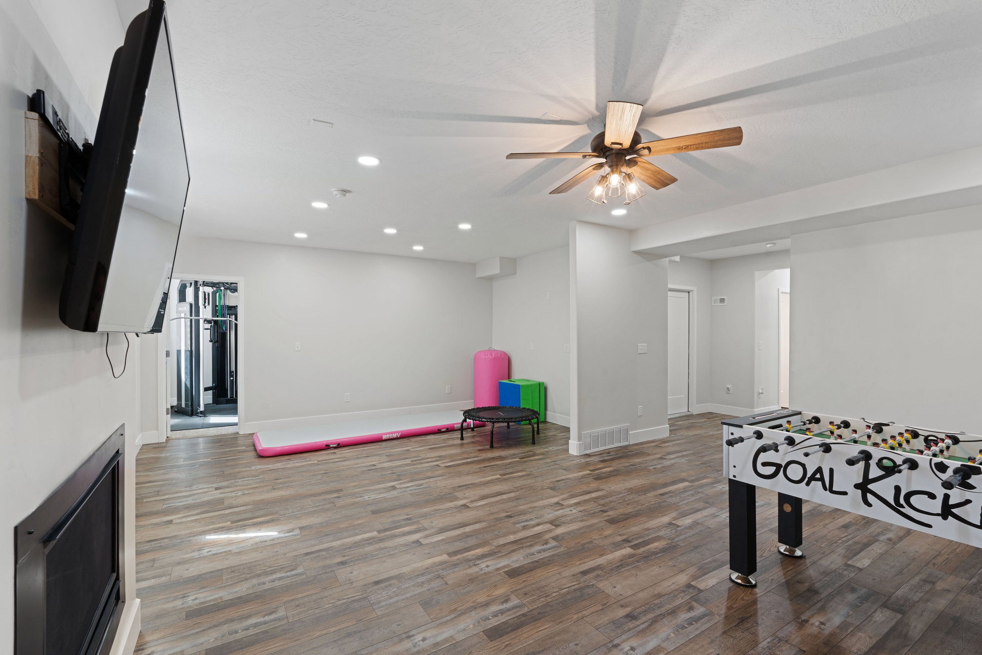 Basement spacious entertainment area featuring wood-finish flooring, recessed lighting, and a ceiling fan with integrated lighting