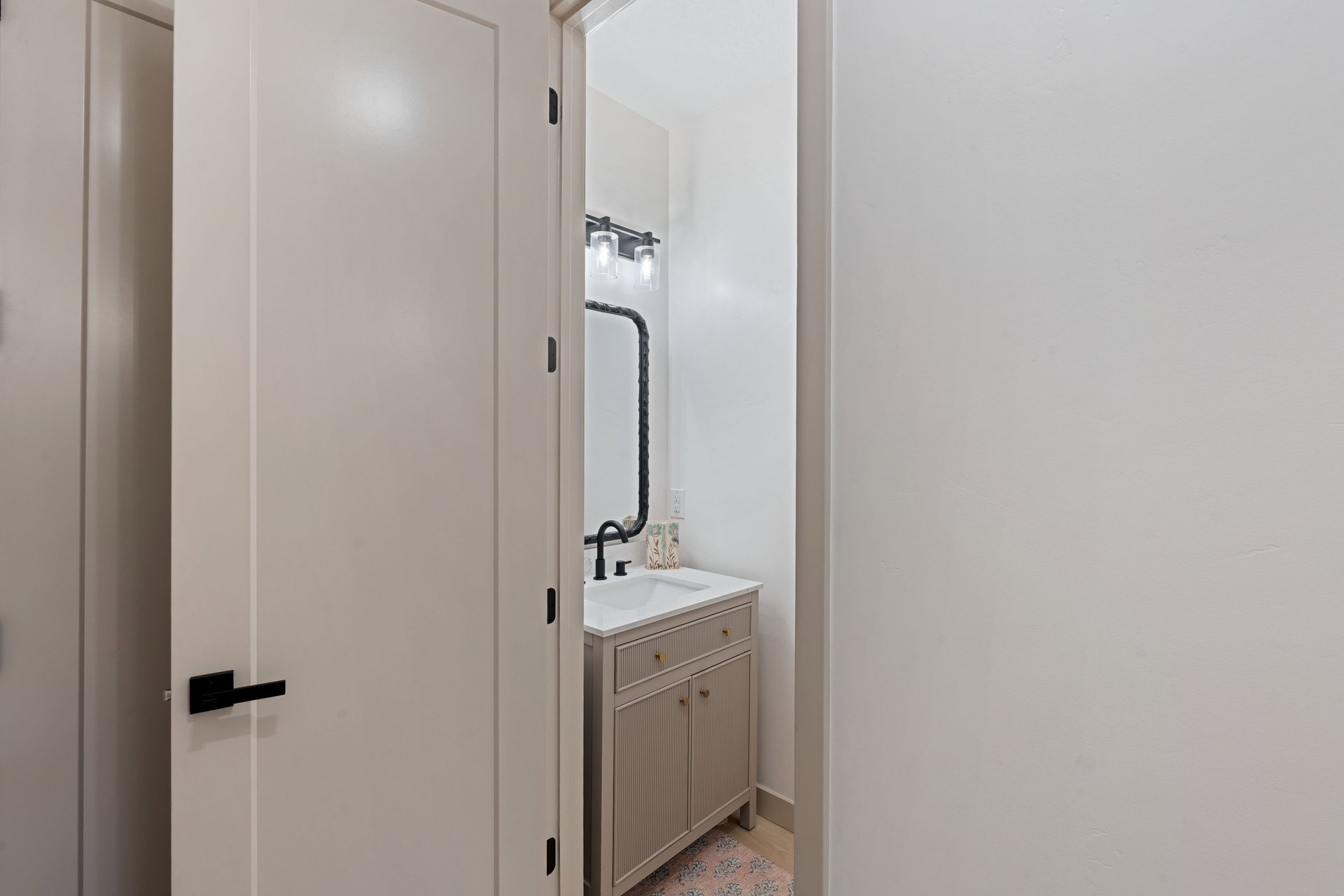 Powder room featuring a single vanity with a white countertop, undermount sink, and matte black faucet