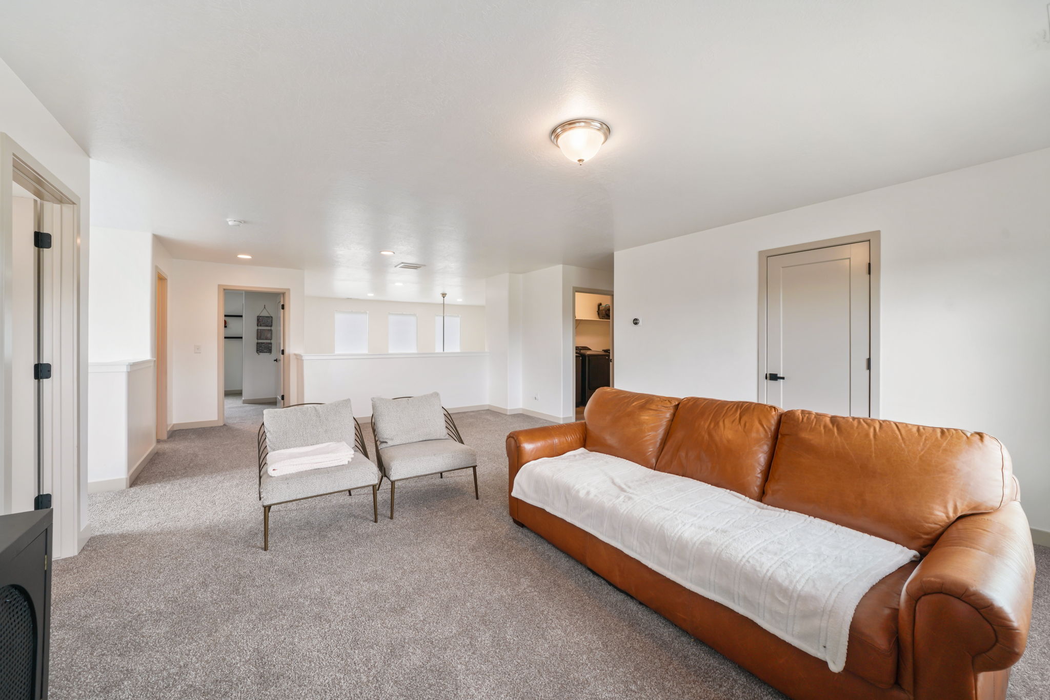 Spacious upper-level area featuring neutral gray carpeting and white walls with wainscoting detail