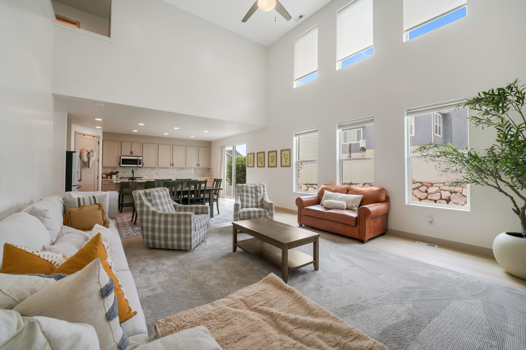 Two-story living area with high ceilings, multiple upper-level windows, and a ceiling fan