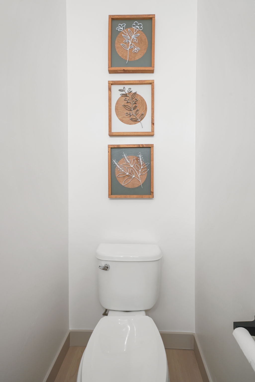 Crisp white walls frame a modern commode, complemented by light wood-finish flooring