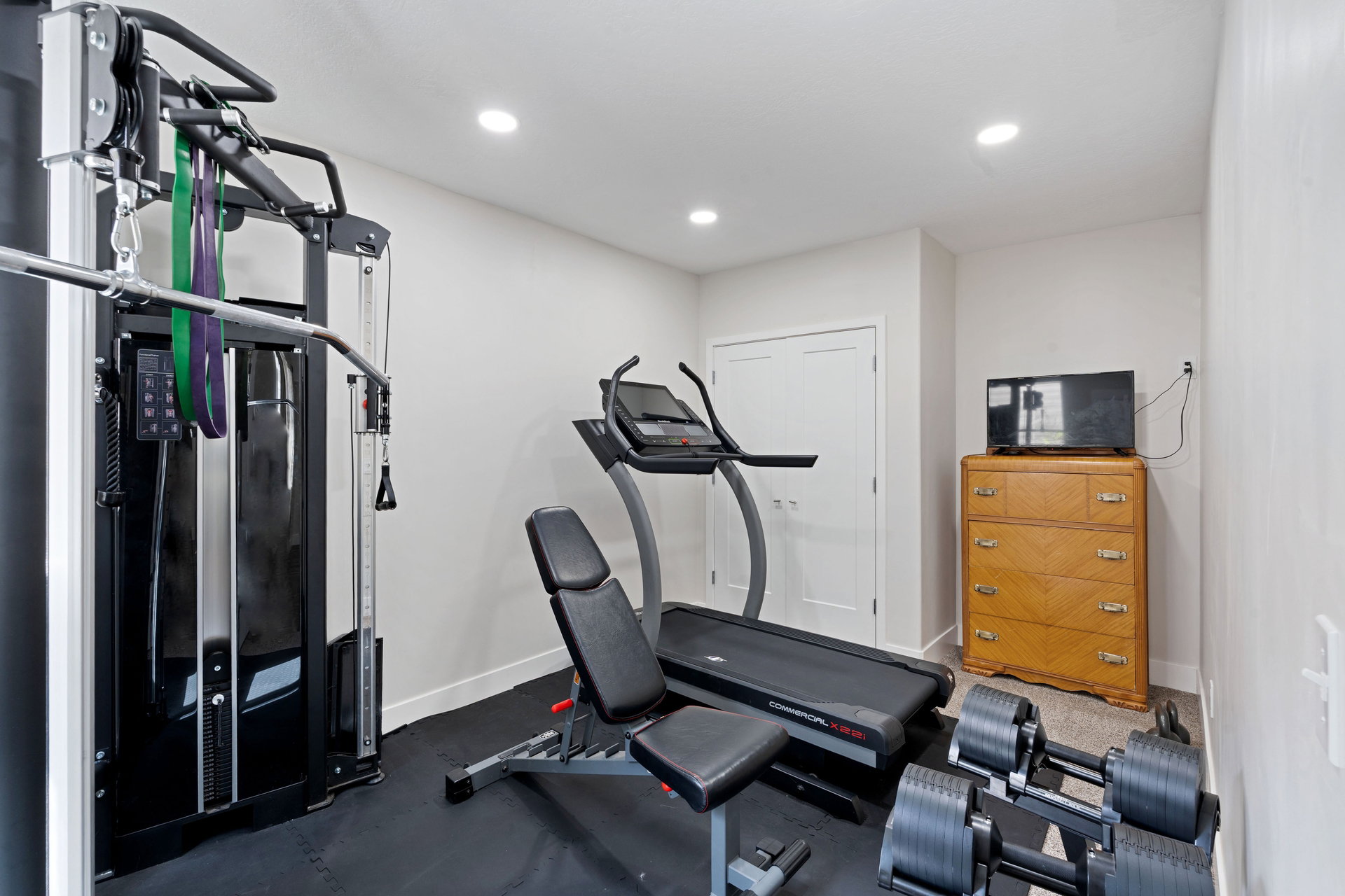 Basement dedicated fitness space or bedroom featuring a black rubber flooring system and recessed ceiling lighting