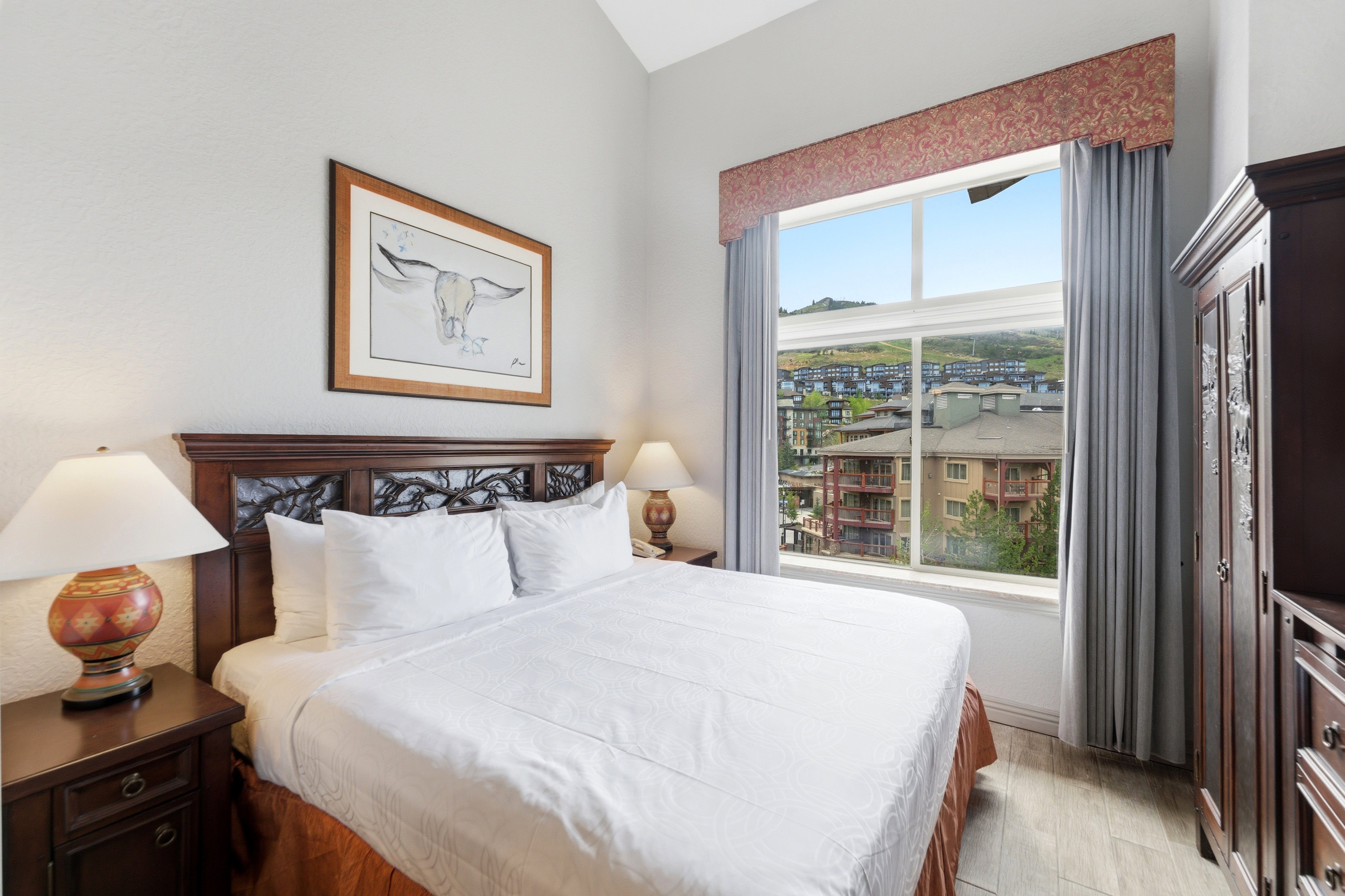 Bedroom featuring a decorative wood headboard, a picture window, and wood-finish flooring