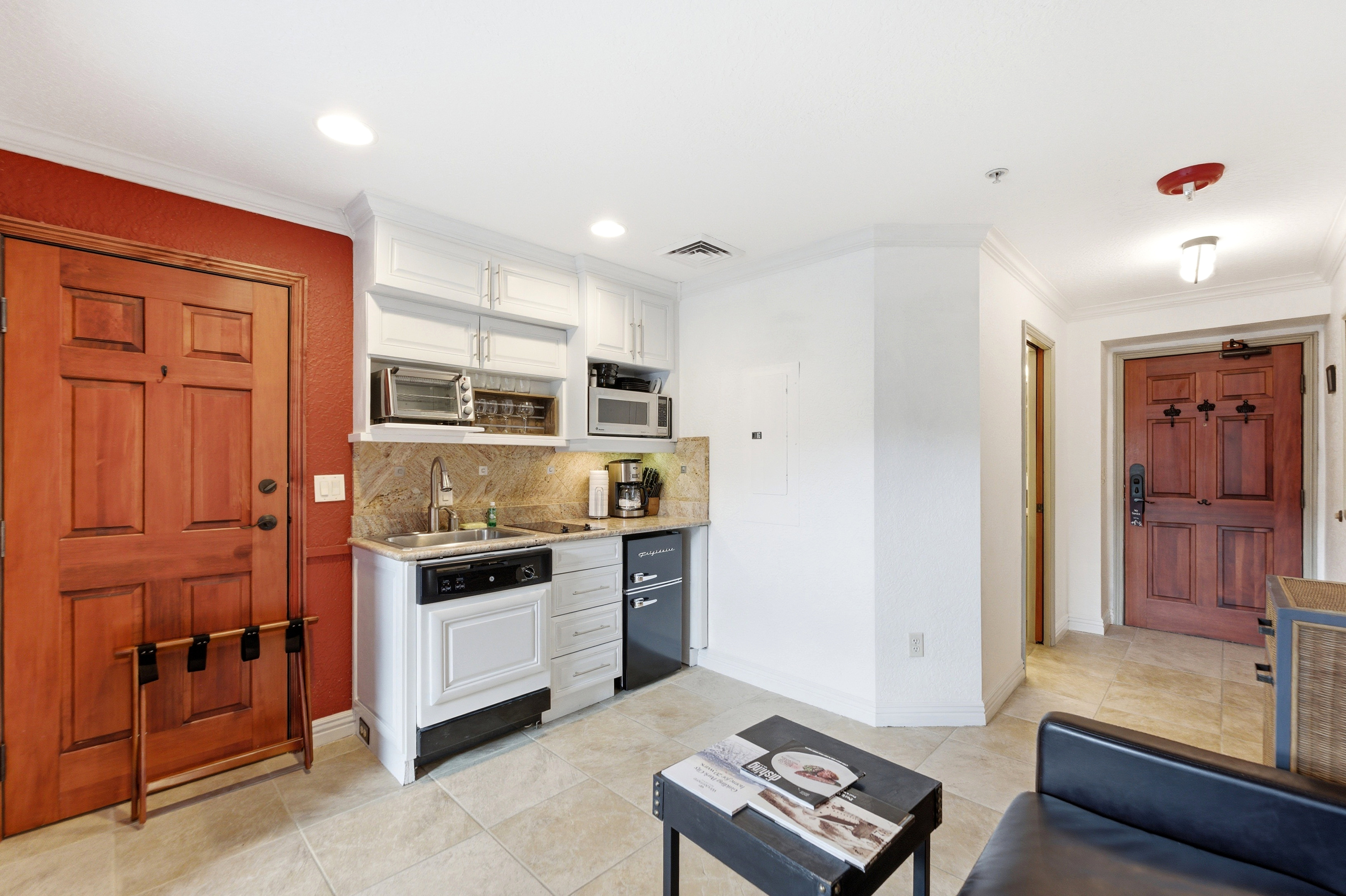 Compact kitchen area featuring white cabinetry, a built-in dishwasher, and a stone-finish countertop with an undermount sink