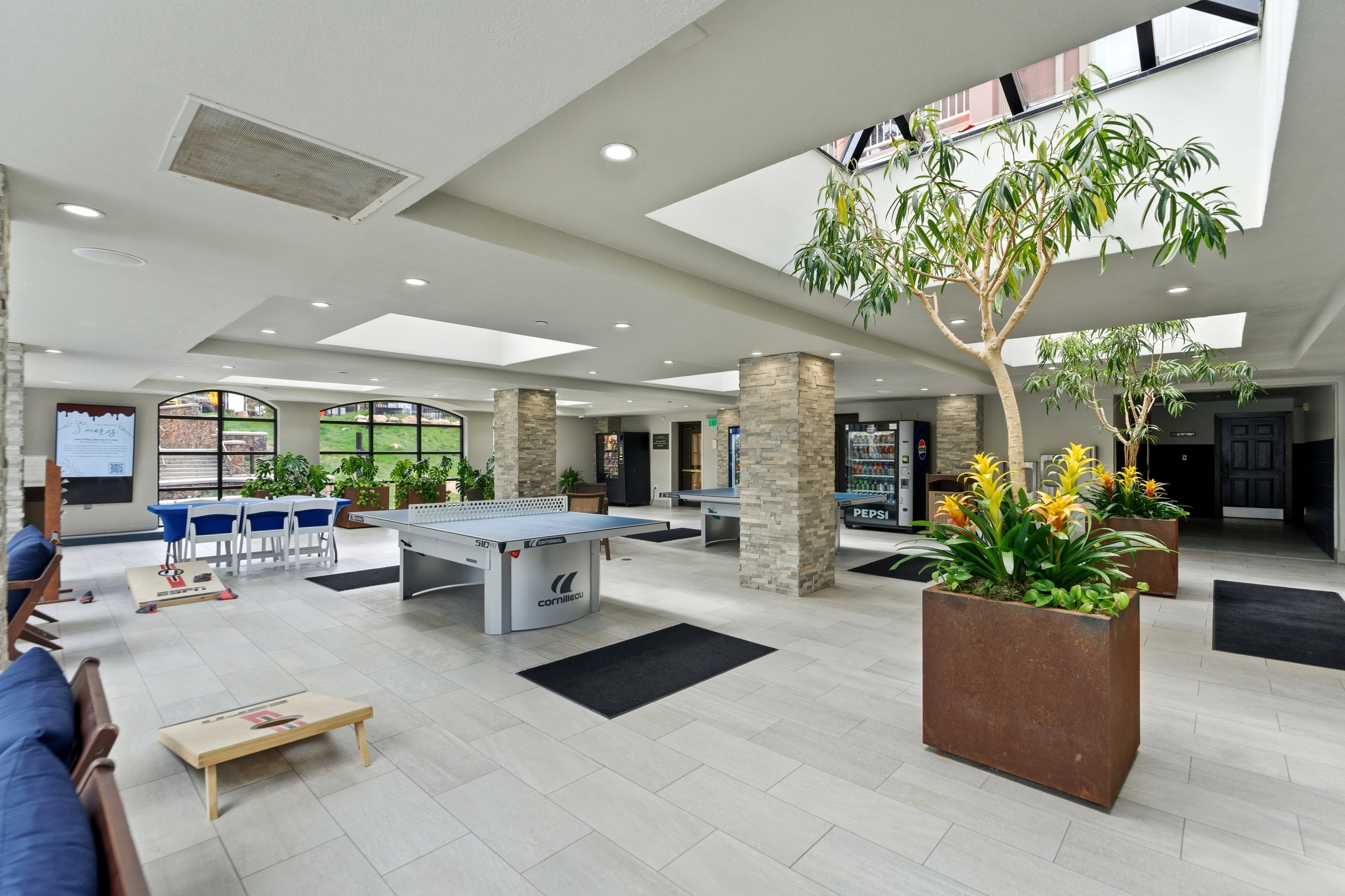 Spacious common area featuring light-toned tile flooring, recessed lighting, and multiple skylights