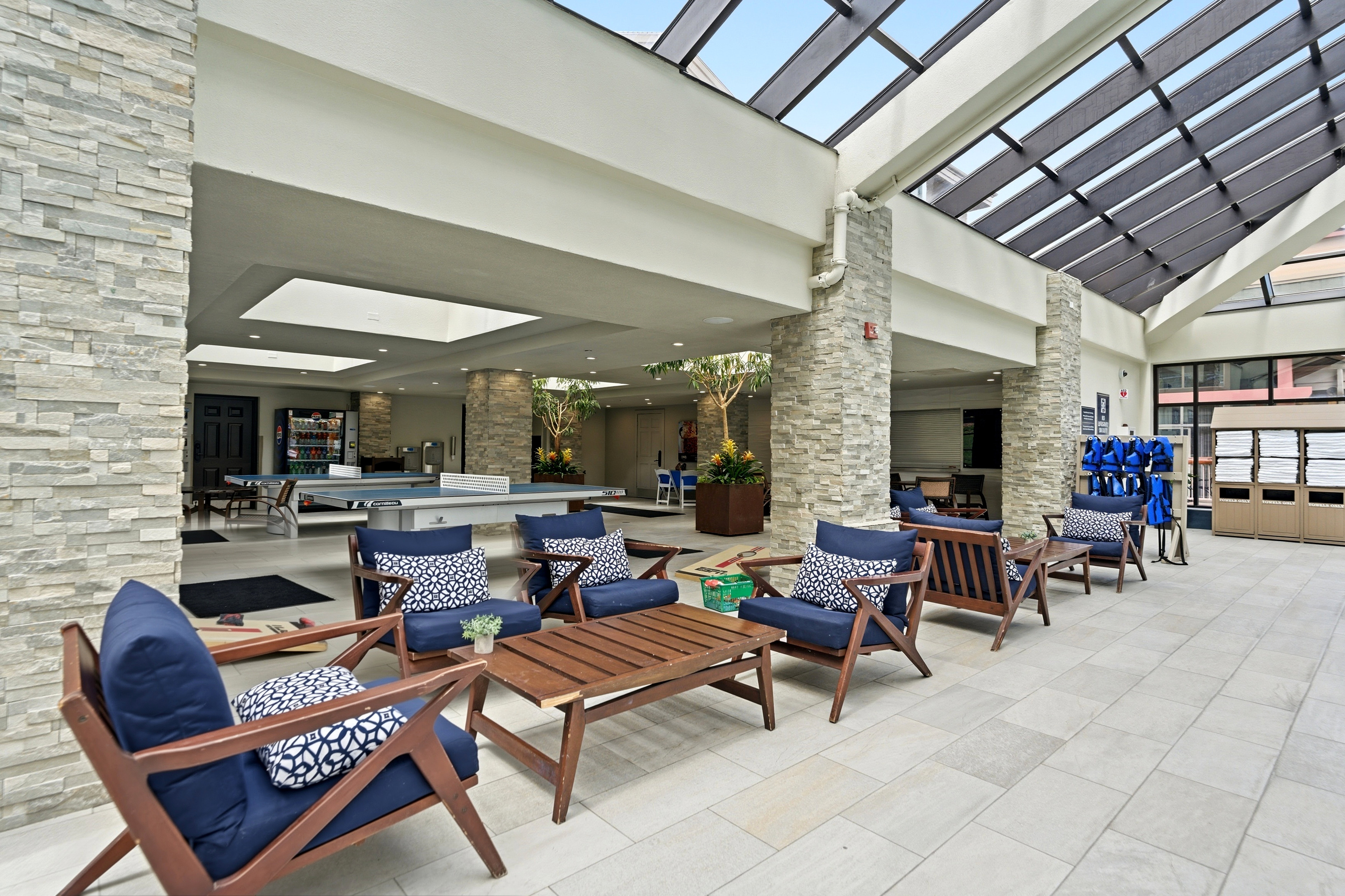 Spacious indoor atrium featuring a full-glass skylight, textured stacked stone columns, and light-toned tile flooring