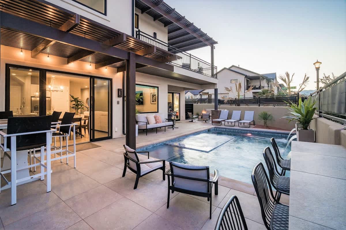 Outdoor living space featuring a custom-shaped pool with integrated spa and waterfall, surrounded by concrete paver patio