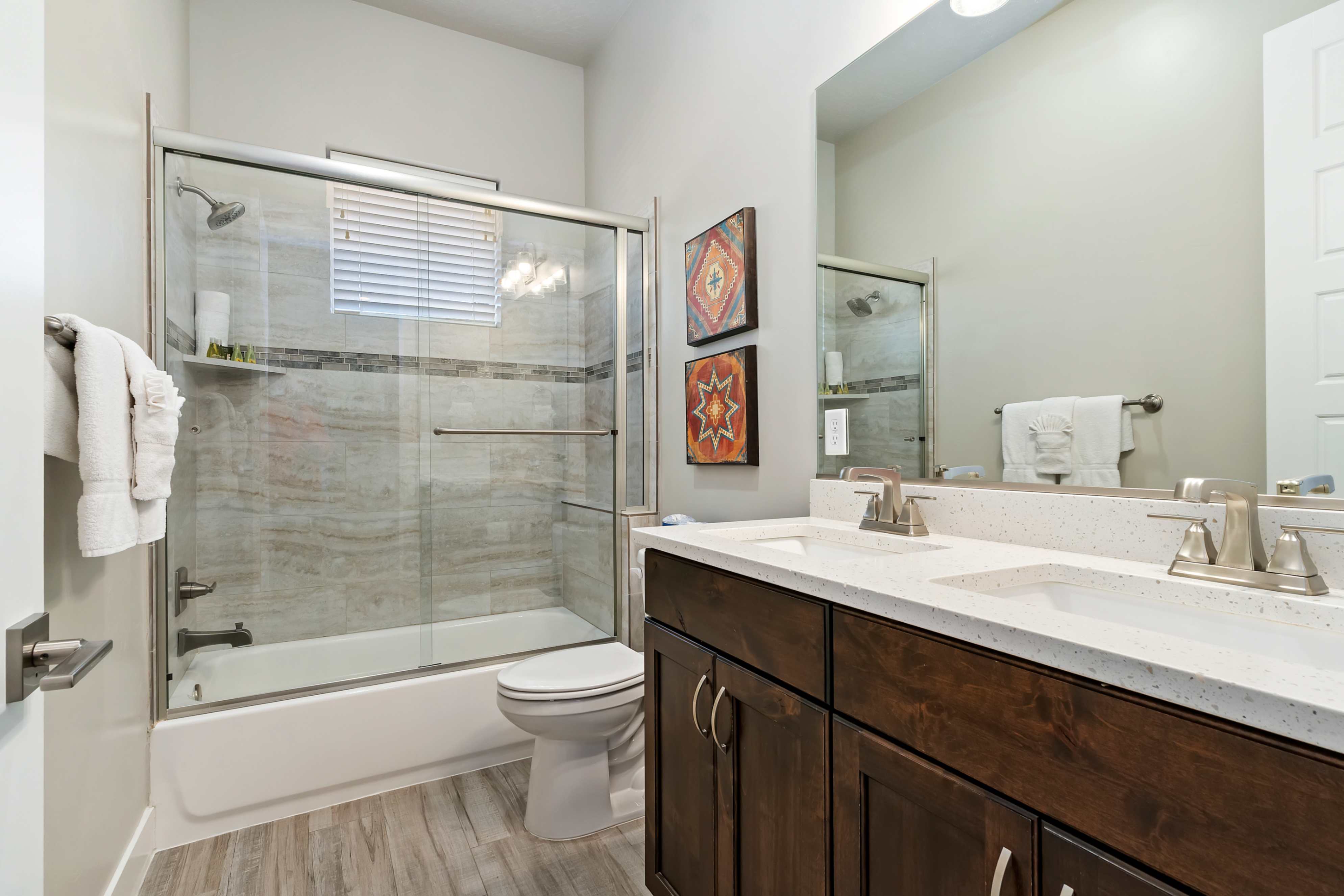 Bathroom featuring a dual-sink vanity with white countertops, dark wood cabinetry, and brushed nickel fixtures