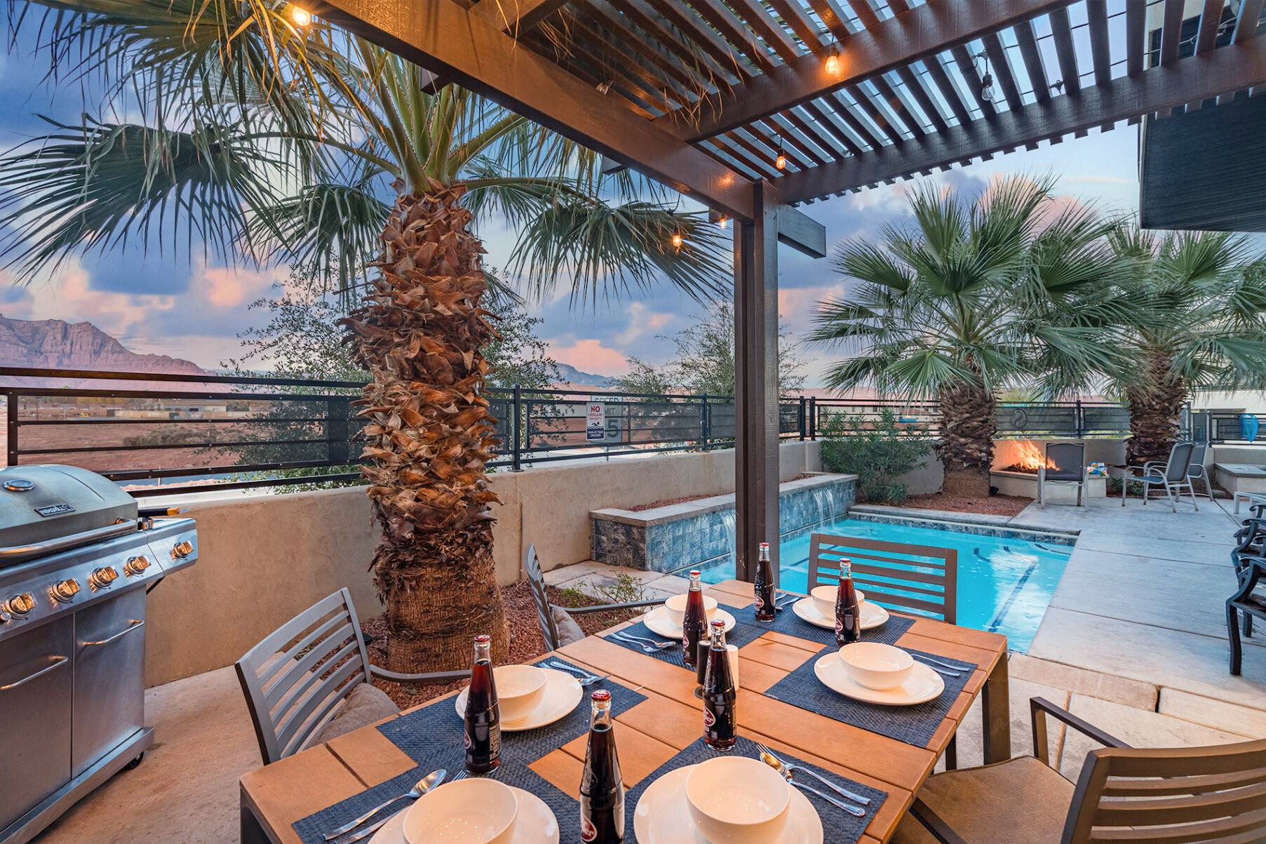 Outdoor patio featuring a slatted pergola with string lighting, a built-in pool, a water feature, and mature palm trees