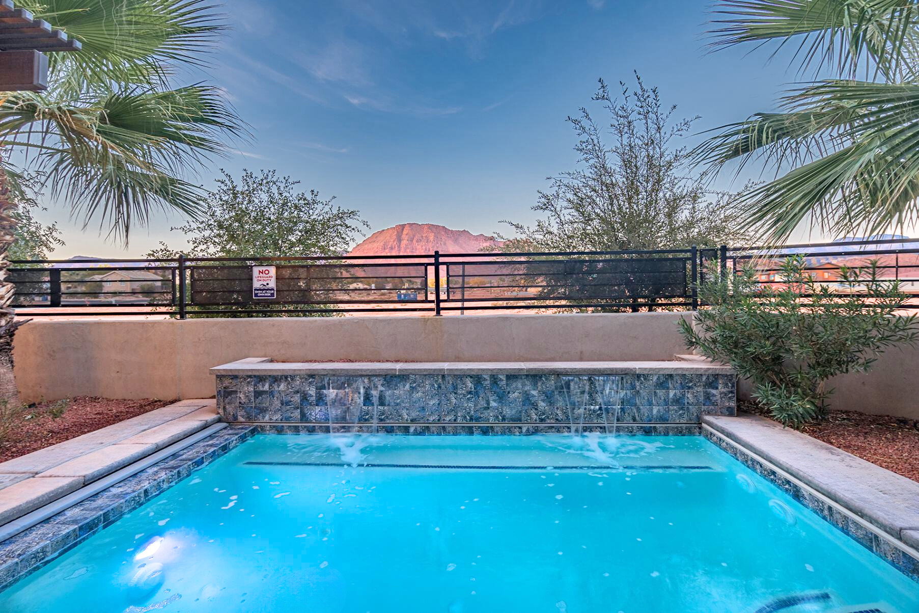 Resort-style pool featuring a waterfall, tiled spa, and surrounding hardscaping