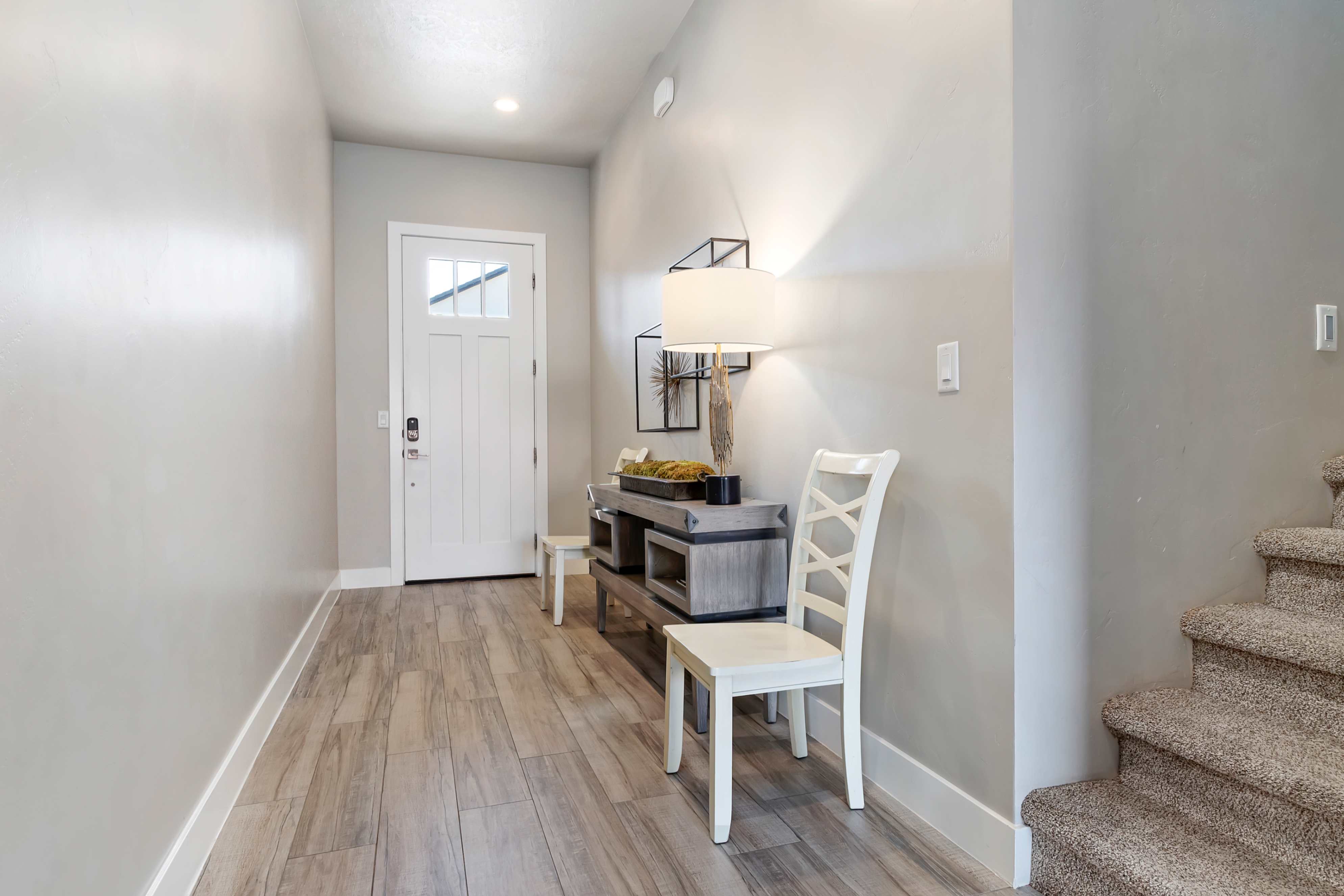 Entryway featuring a white paneled door with upper glass inserts, wood-finish flooring, recessed lighting, and a carpeted staircase