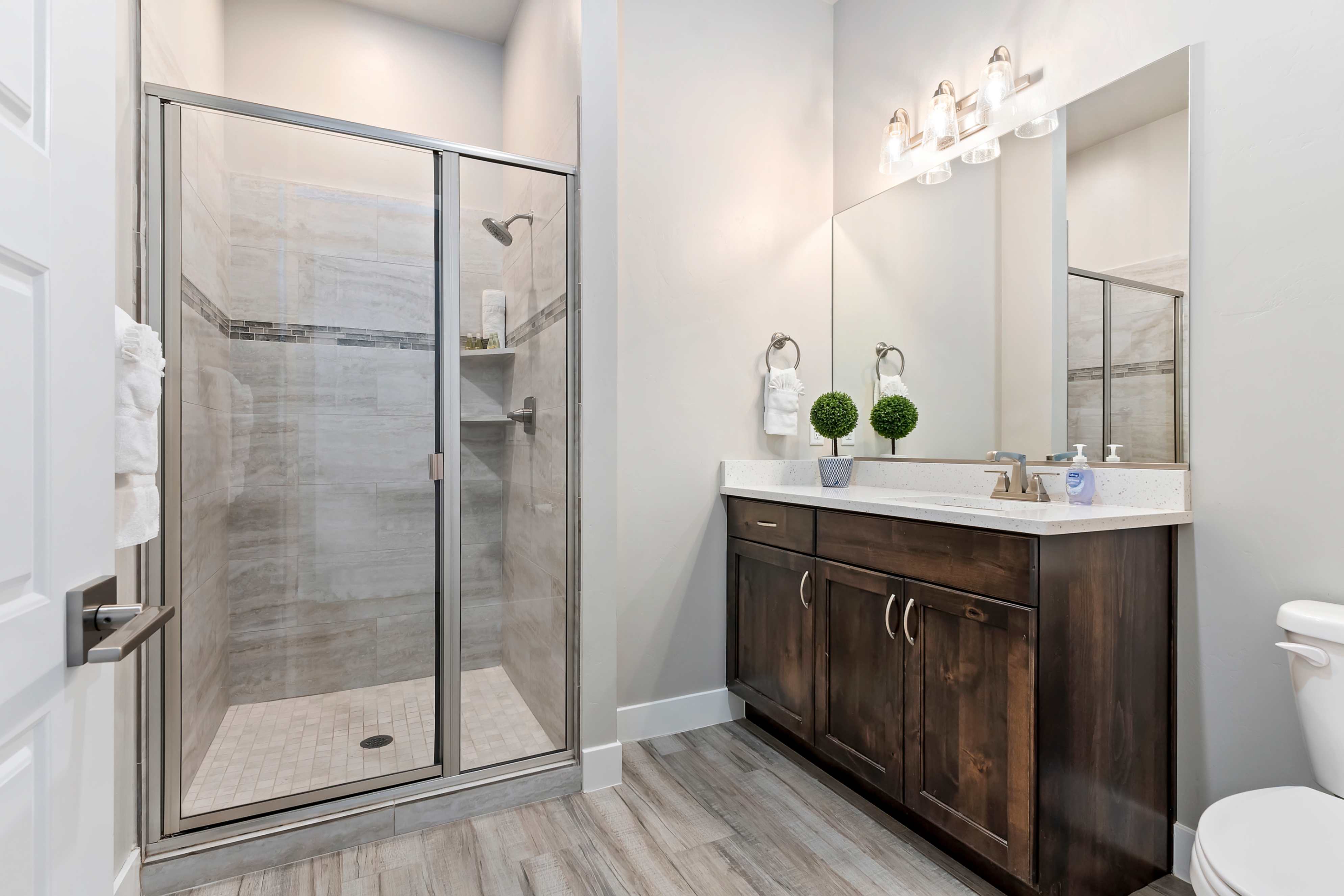 Walk-in shower with clear glass enclosure and tile surround