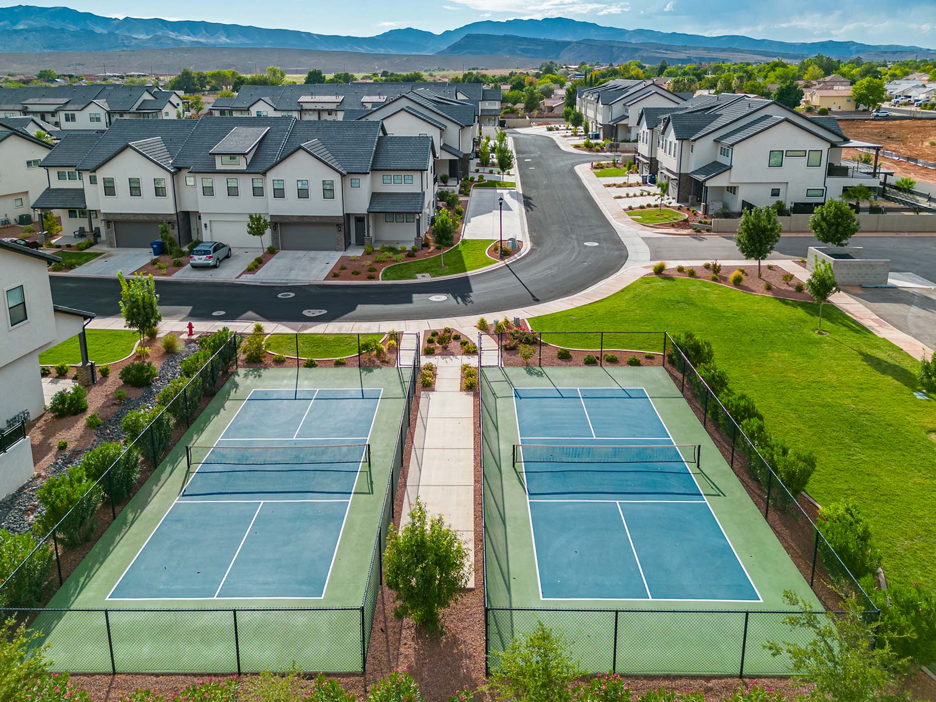 Two fenced pickleball courts featuring blue and green playing surfaces