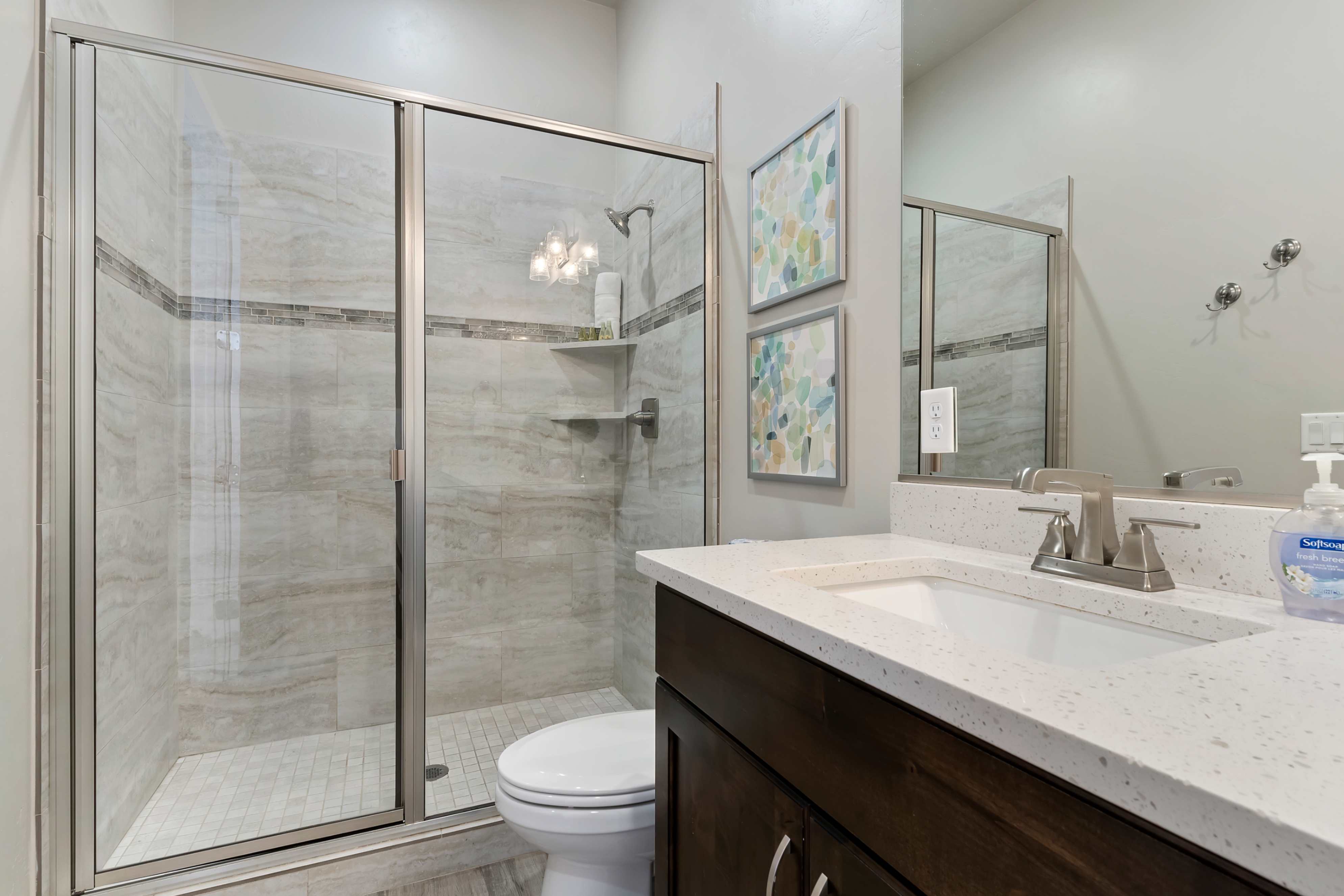 Shower enclosure with glass panels, light-toned tile walls, and a decorative accent tile band