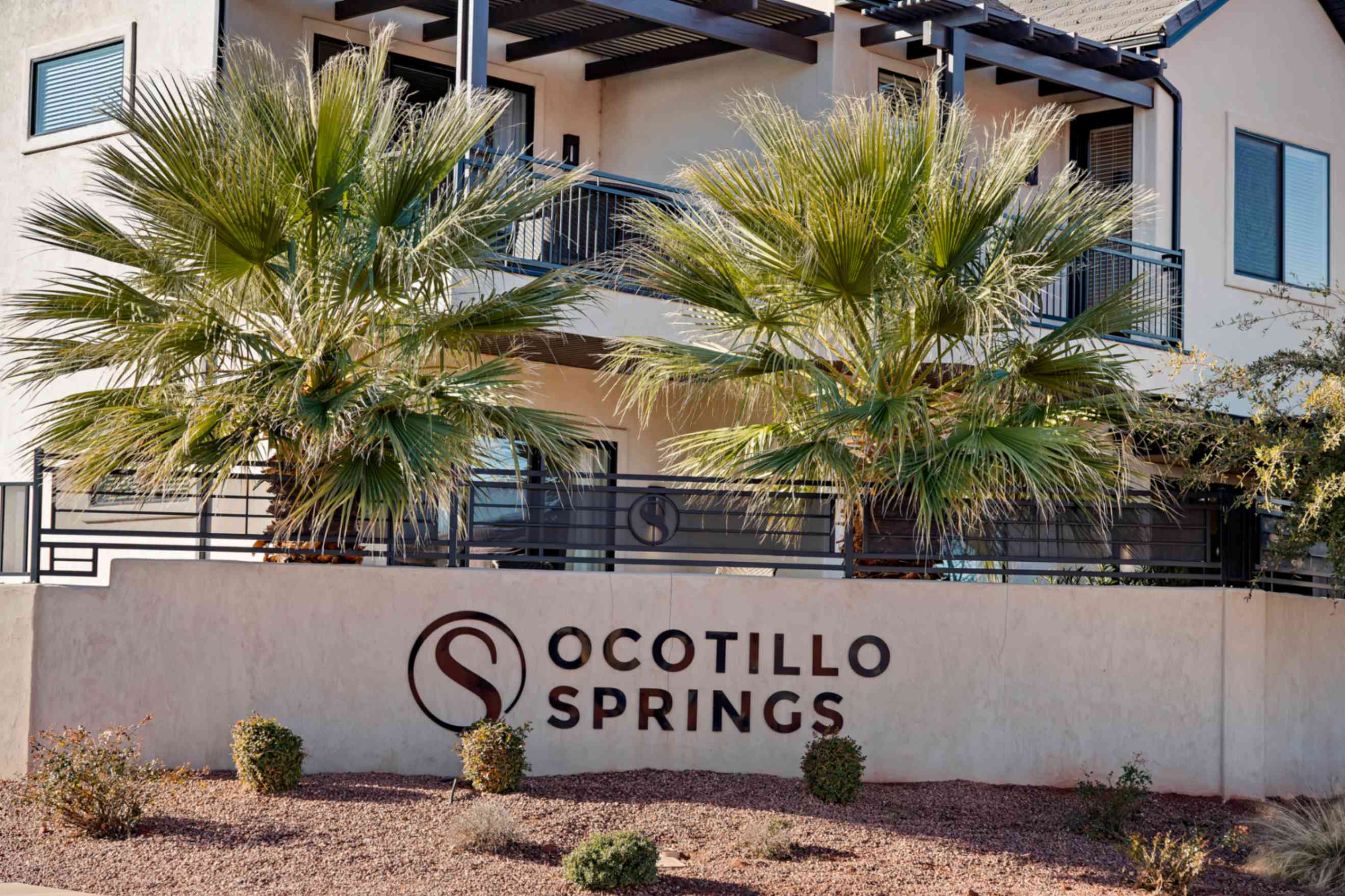 Entry monument featuring the property name, "Ocotillo Springs," set against a desert-style landscape with gravel and low-lying shrubs