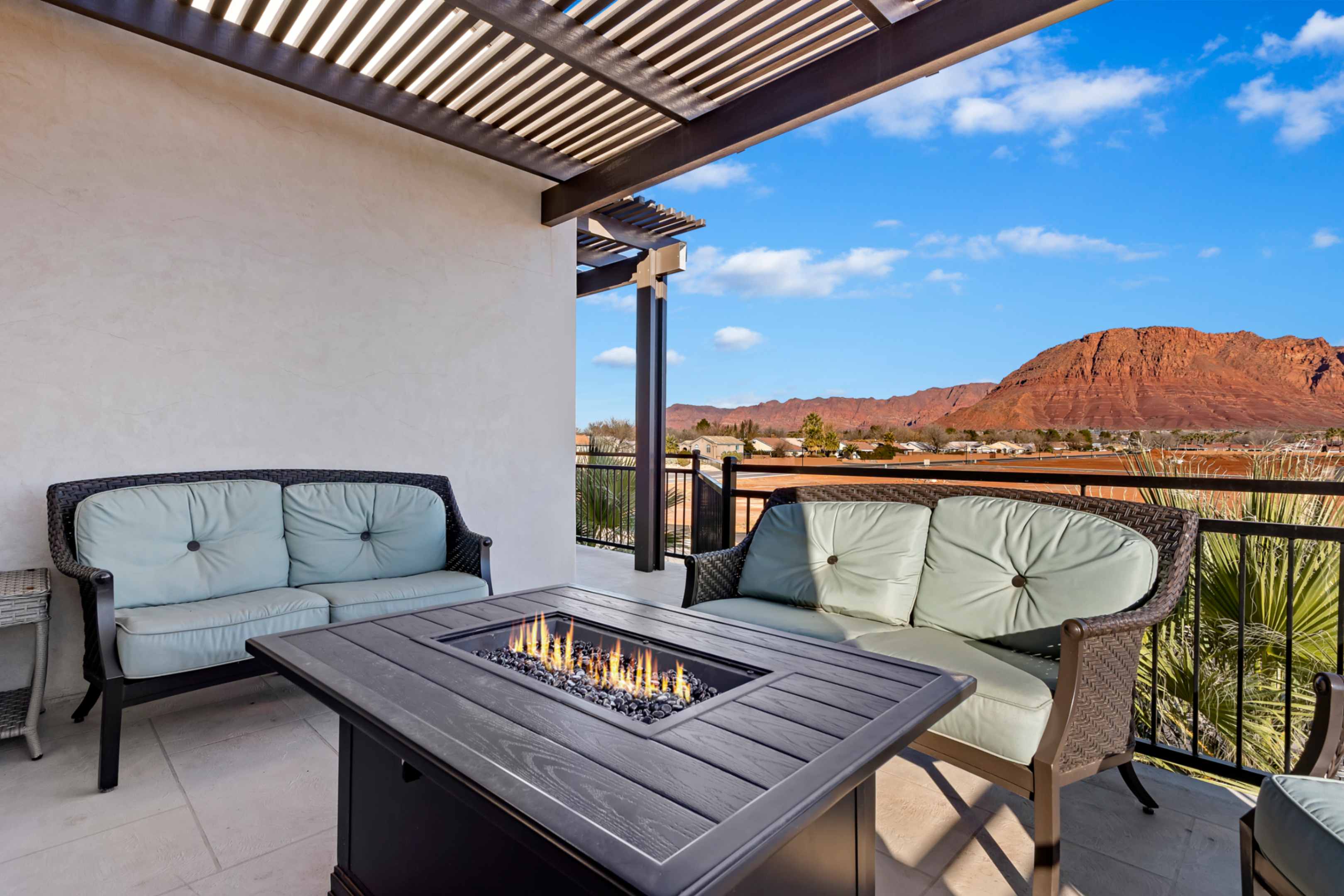 Outdoor patio with a slatted pergola, tile flooring, and a built-in fire pit