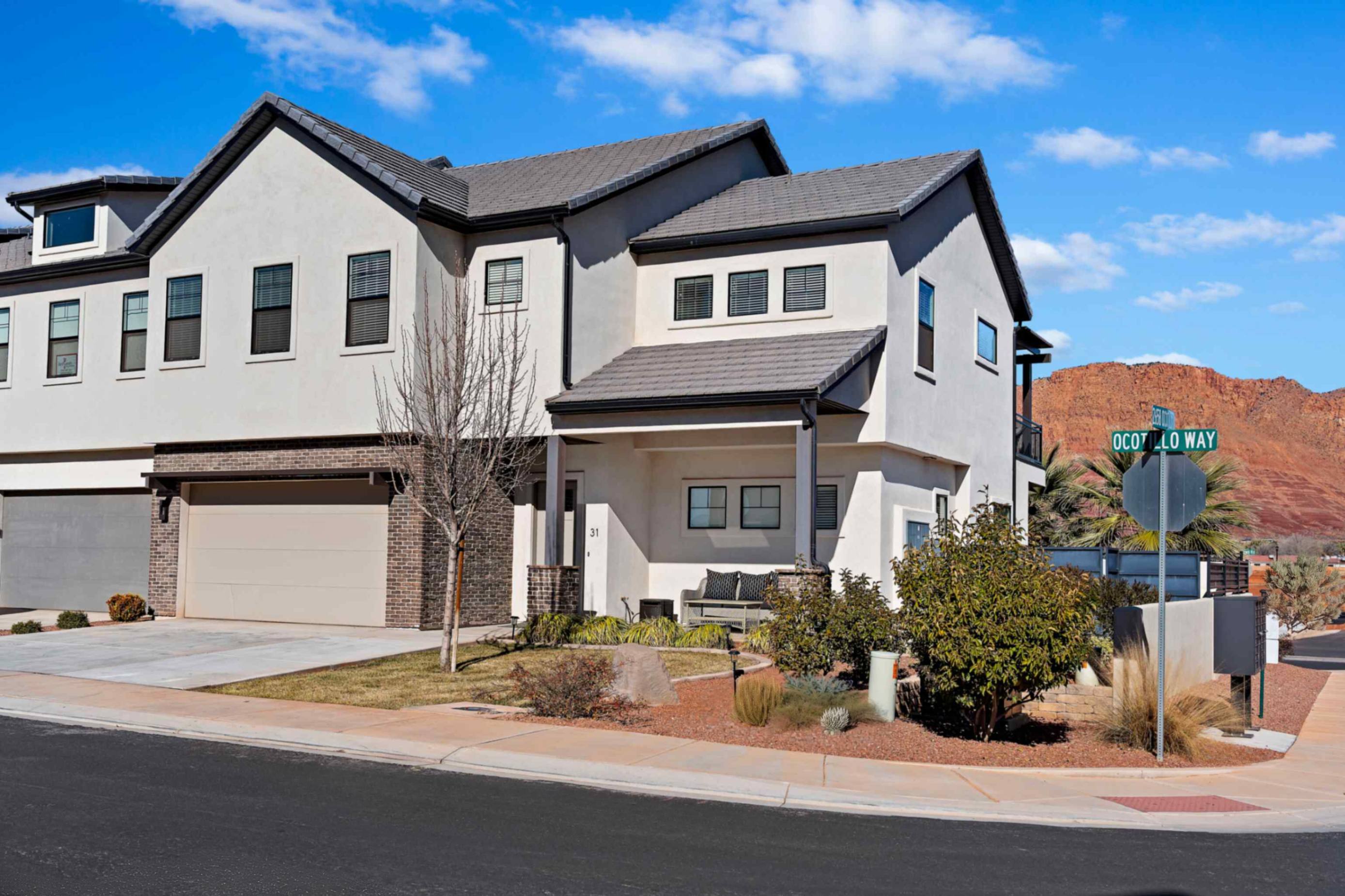 Contemporary stucco exterior featuring a covered entry, dark-framed windows, and an attached garage with a sectional door