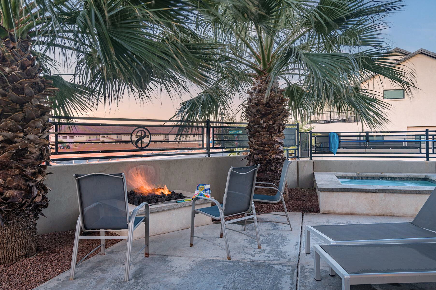 Outdoor patio featuring a built-in fire pit, a hot tub, and two mature palm trees