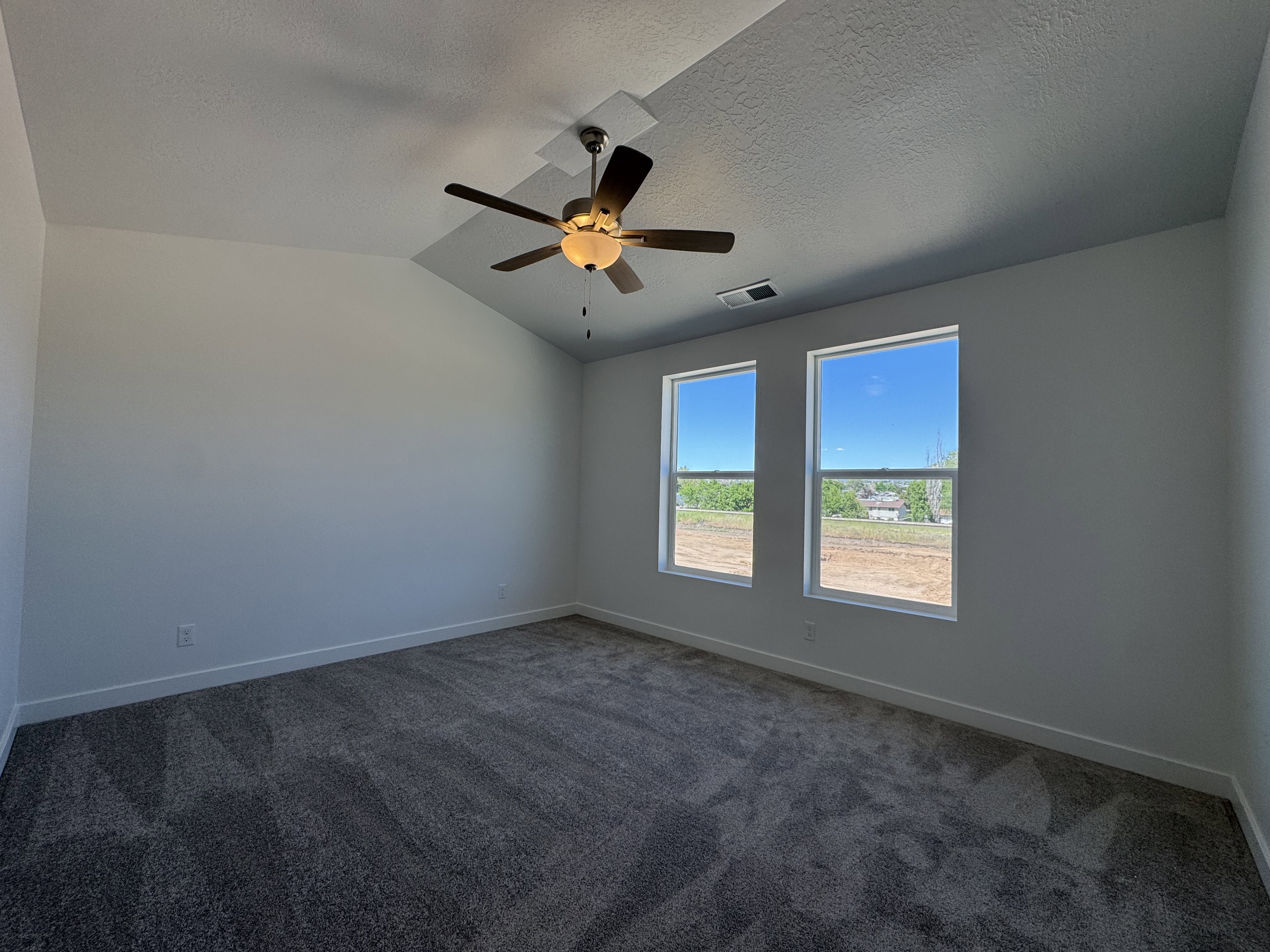 Carpeted interior space featuring a vaulted ceiling and a ceiling fan with integrated lighting