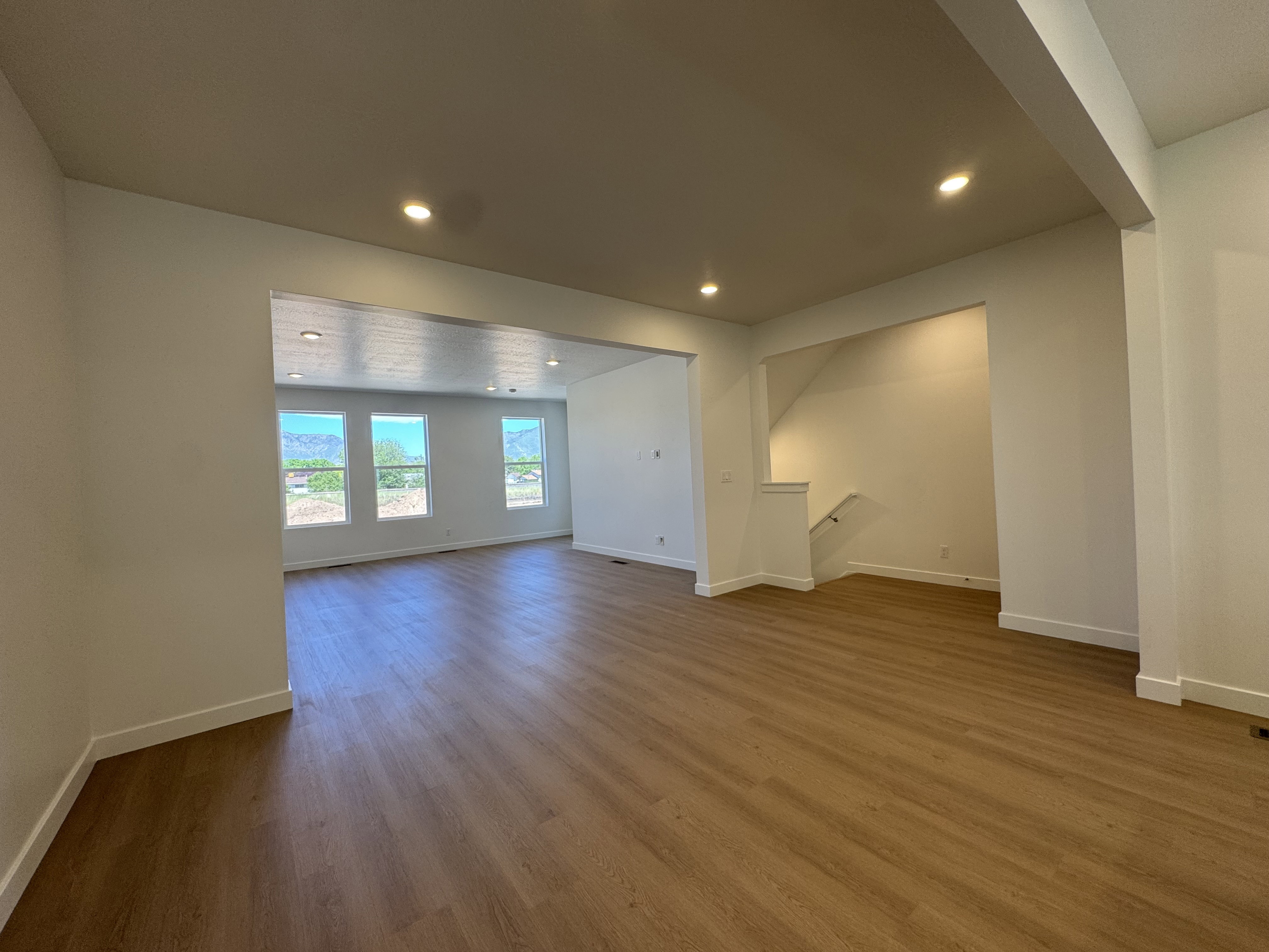 Spacious interior featuring wood-finish flooring throughout, recessed lighting, and white baseboards