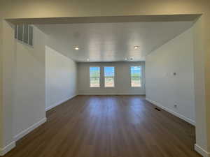 Spacious room with wood-finish flooring, recessed lighting, and three tall windows
