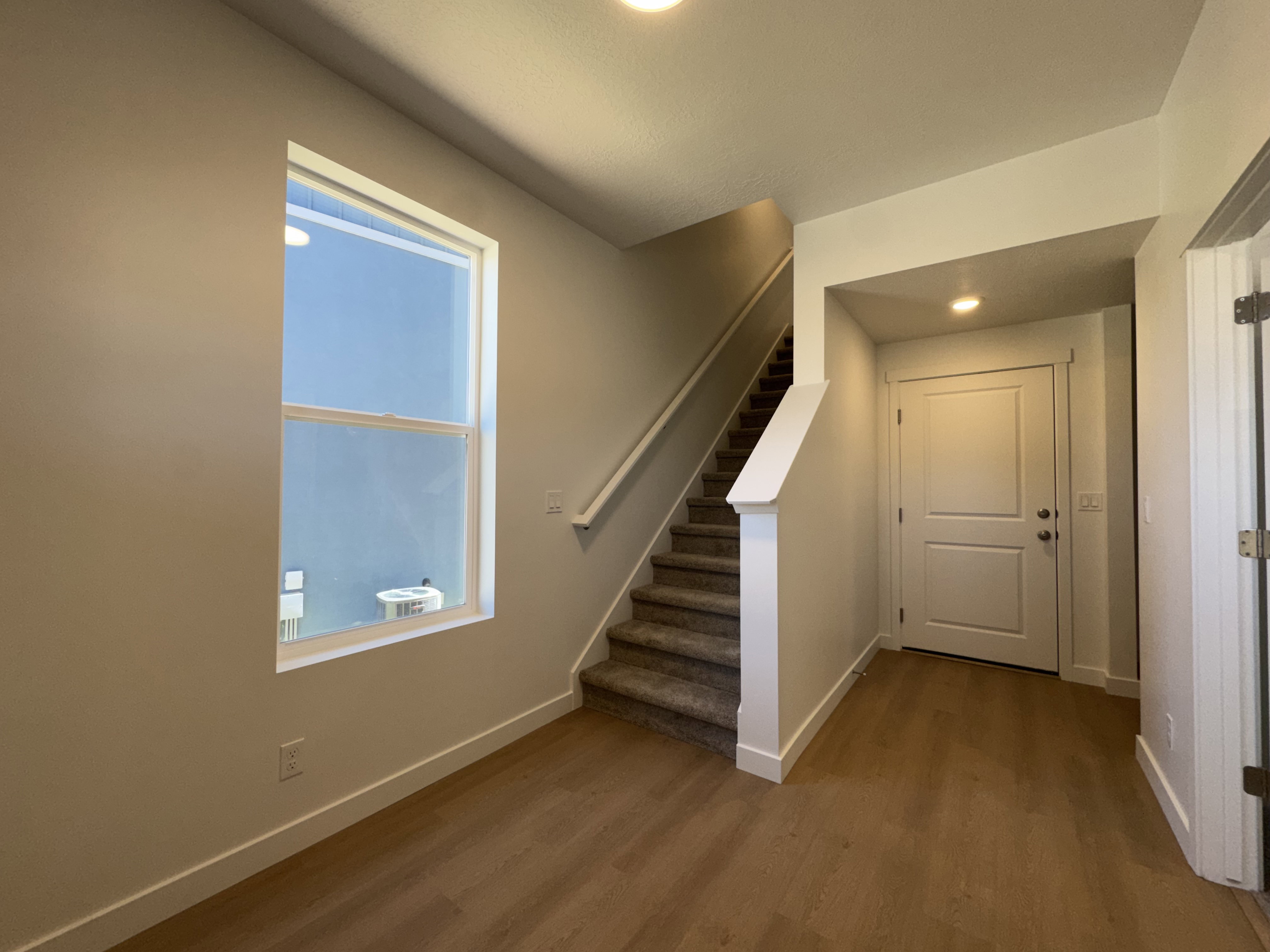 Entryway featuring wood-finish flooring, a large window, a carpeted staircase, and a paneled door