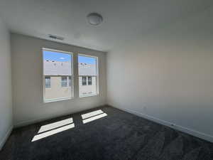 Bedroom featuring two large windows, textured carpeting, white walls, white baseboards, and a flush-mount ceiling light fixture