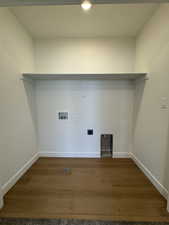 Dedicated laundry area featuring wood-finish flooring, white walls, and a built-in overhead shelf