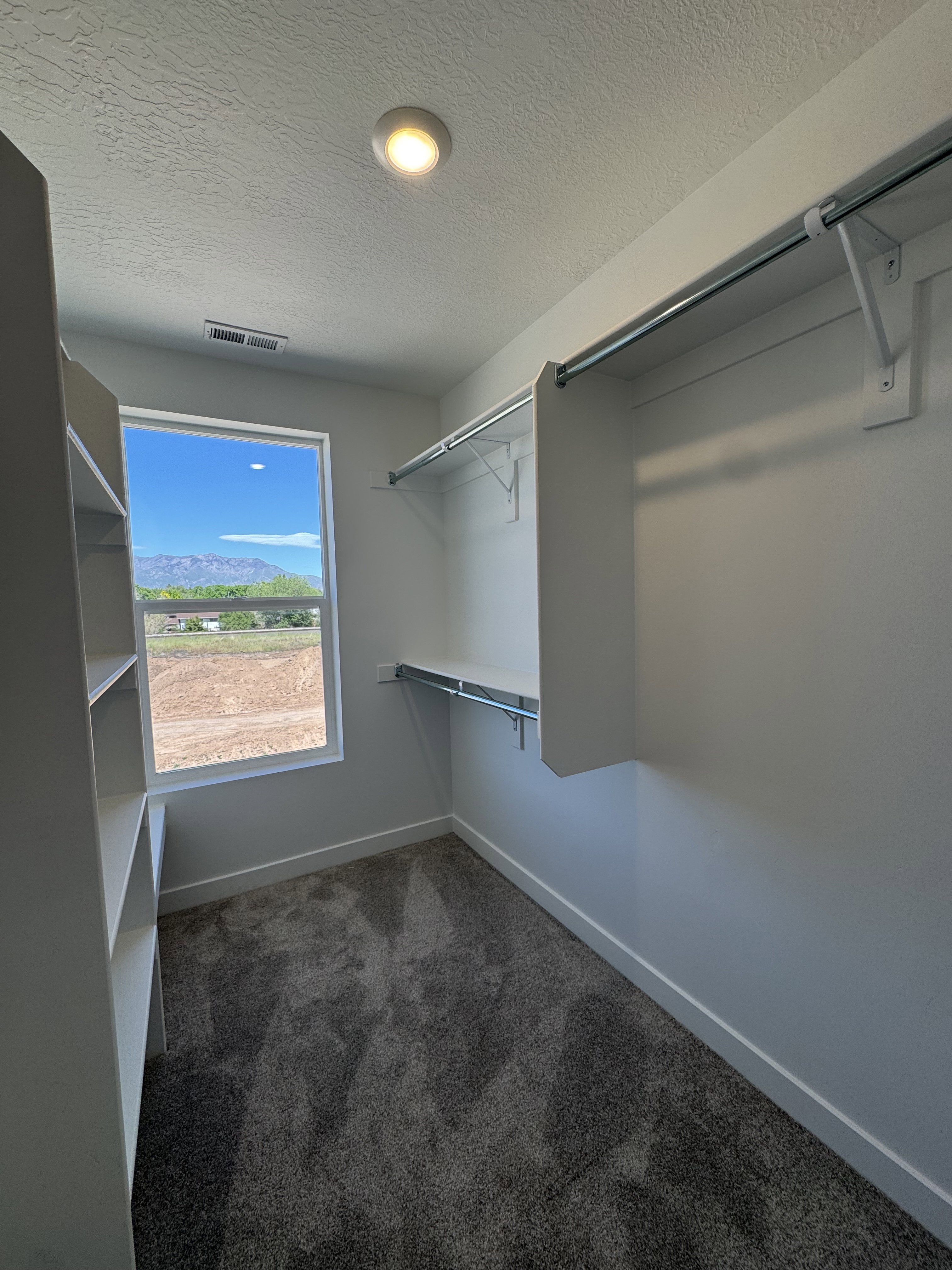 Walk-in closet featuring built-in shelving, hanging rods, and a window for natural light