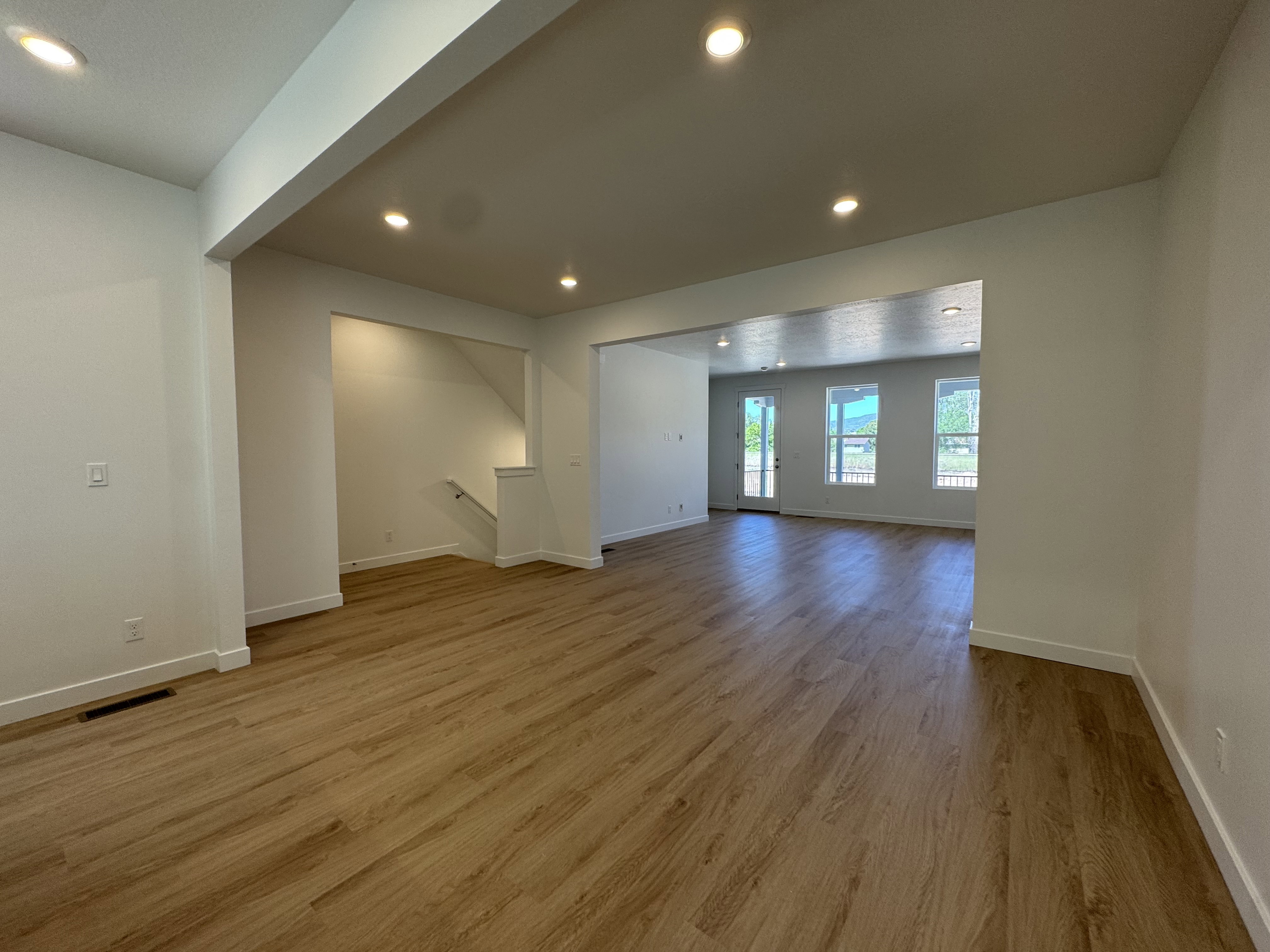 Expansive room featuring wood-finish flooring, recessed lighting, and white baseboards