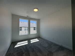 Dual windows providing ample illumination, plush carpet flooring, white painted walls, white baseboards, and a ceiling-mounted light fixture
