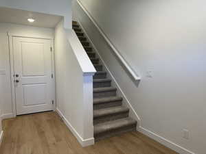 Staircase with carpeted treads and risers, featuring a white handrail and newel post